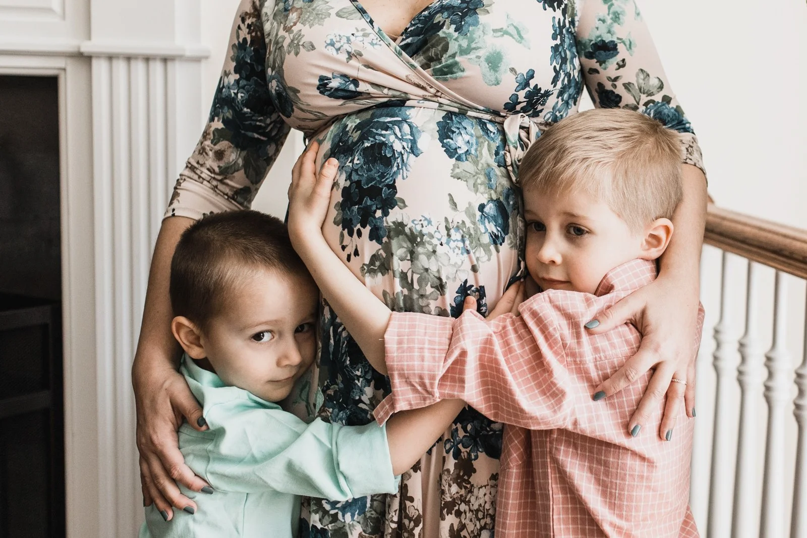close up of 2 young boys hugging their moms pregnant belly