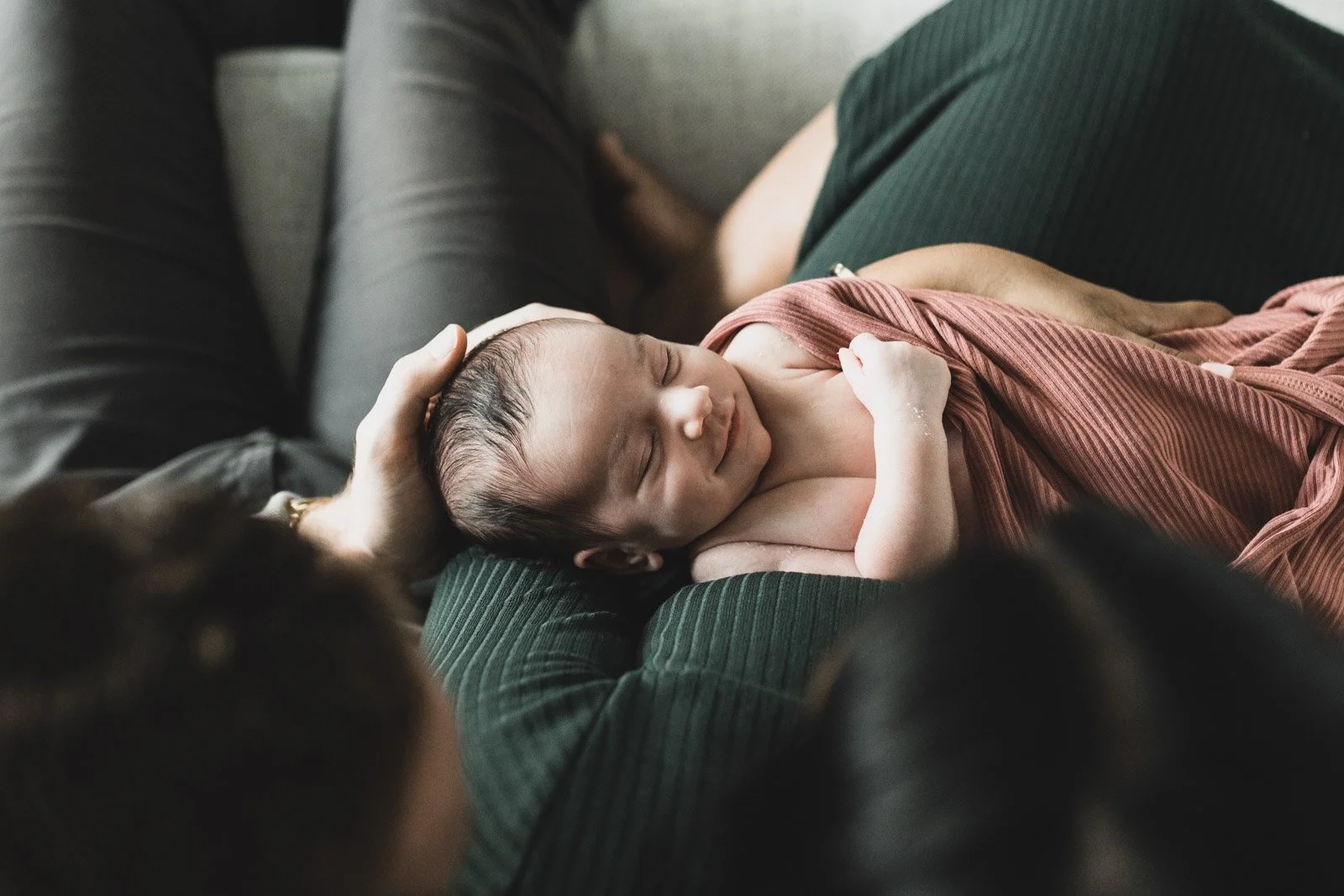 overhead view of newborn baby in parents arms smiling