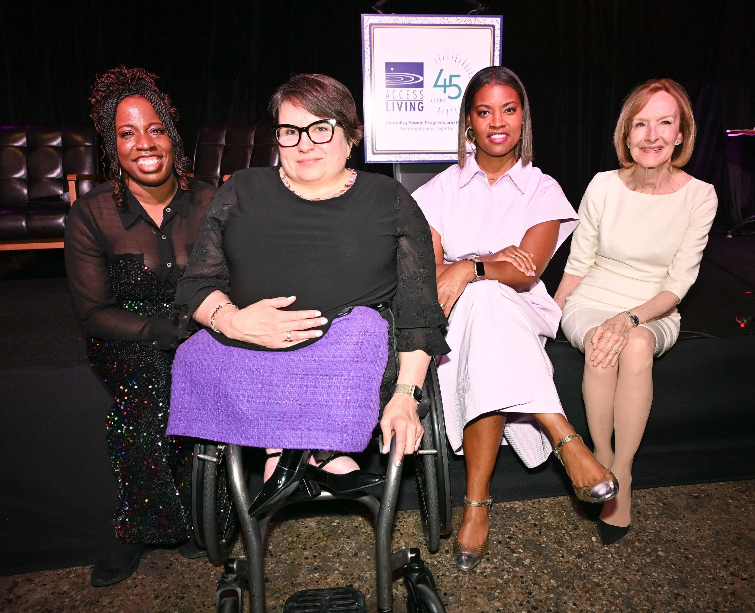 Four women seated side by side at a panel event, with a screen behind them displaying a logo celebrating 45 years of Access Living.