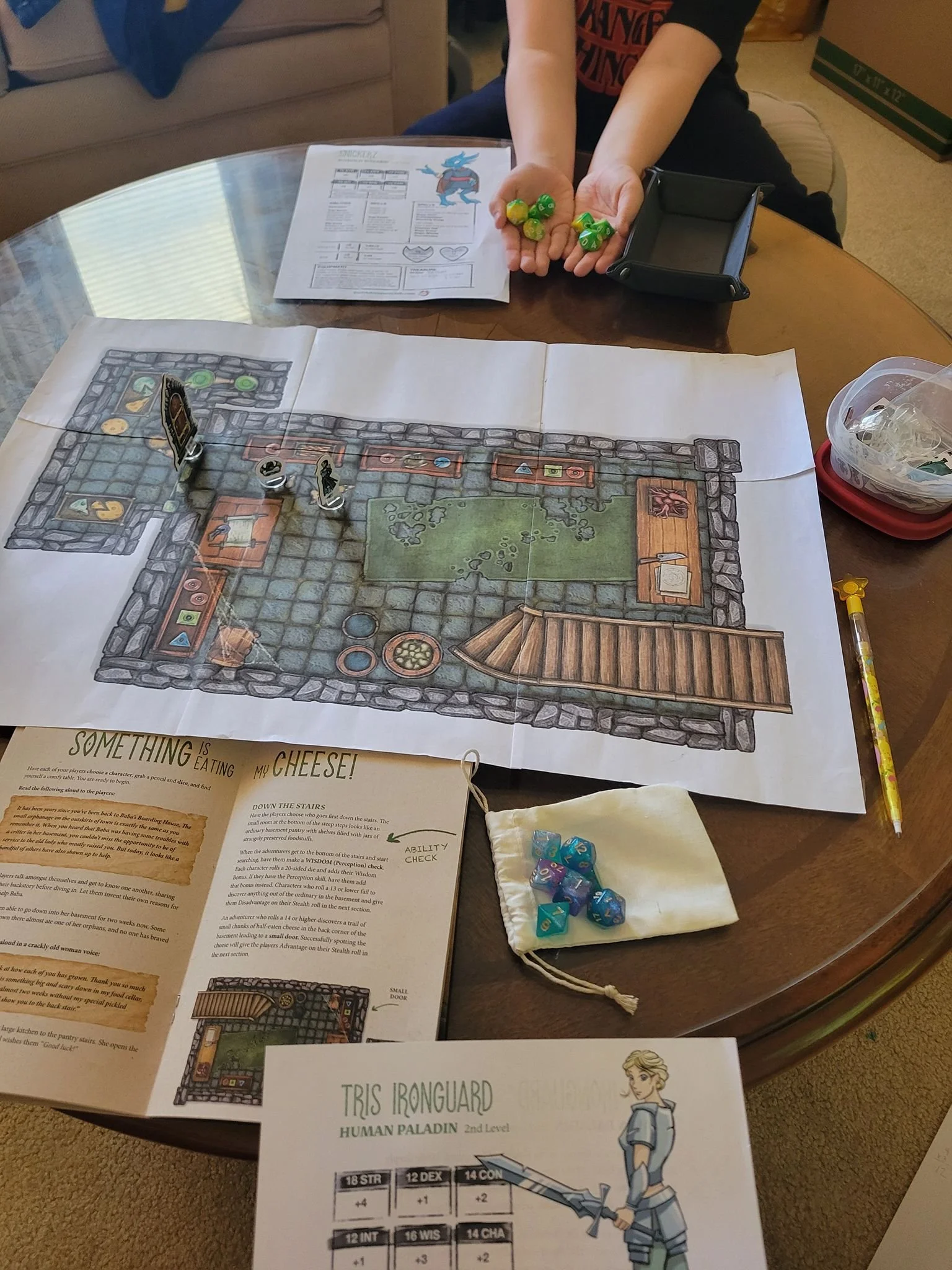 Tabletop role-playing game setup with a game map, character sheet, dice, and game tokens on a round table.