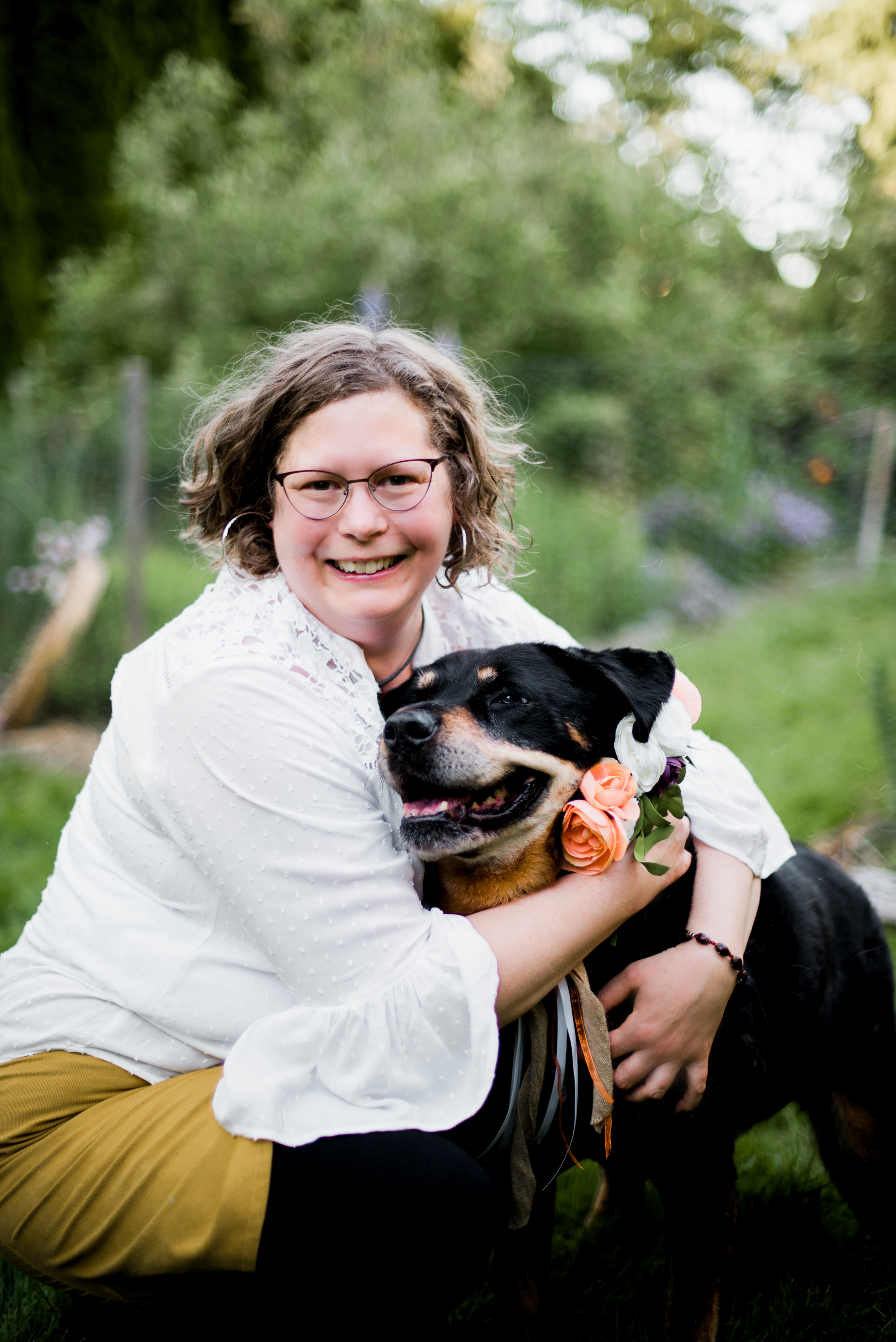 Bellingham, Pet Medium, Joanna siting in the garden talking  and hugging with her tan and black dog  who is smiling