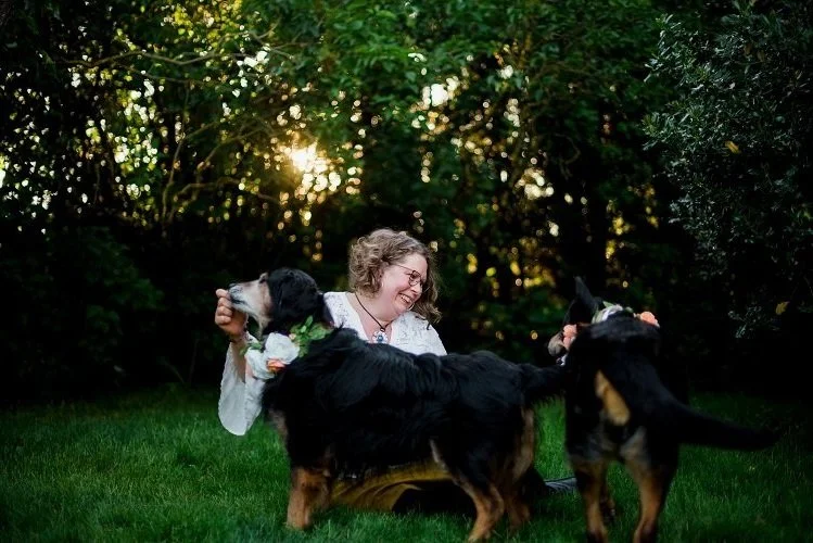 Photo of intuitive animal communicator, Joanna Schmidt and her two recued dogs in the garden eating cookies