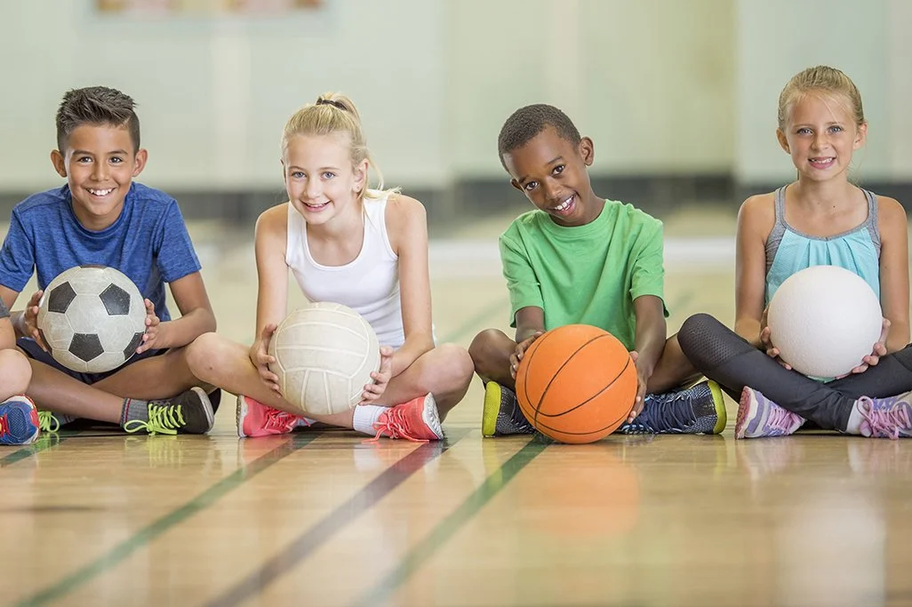 children holding various sports equipment