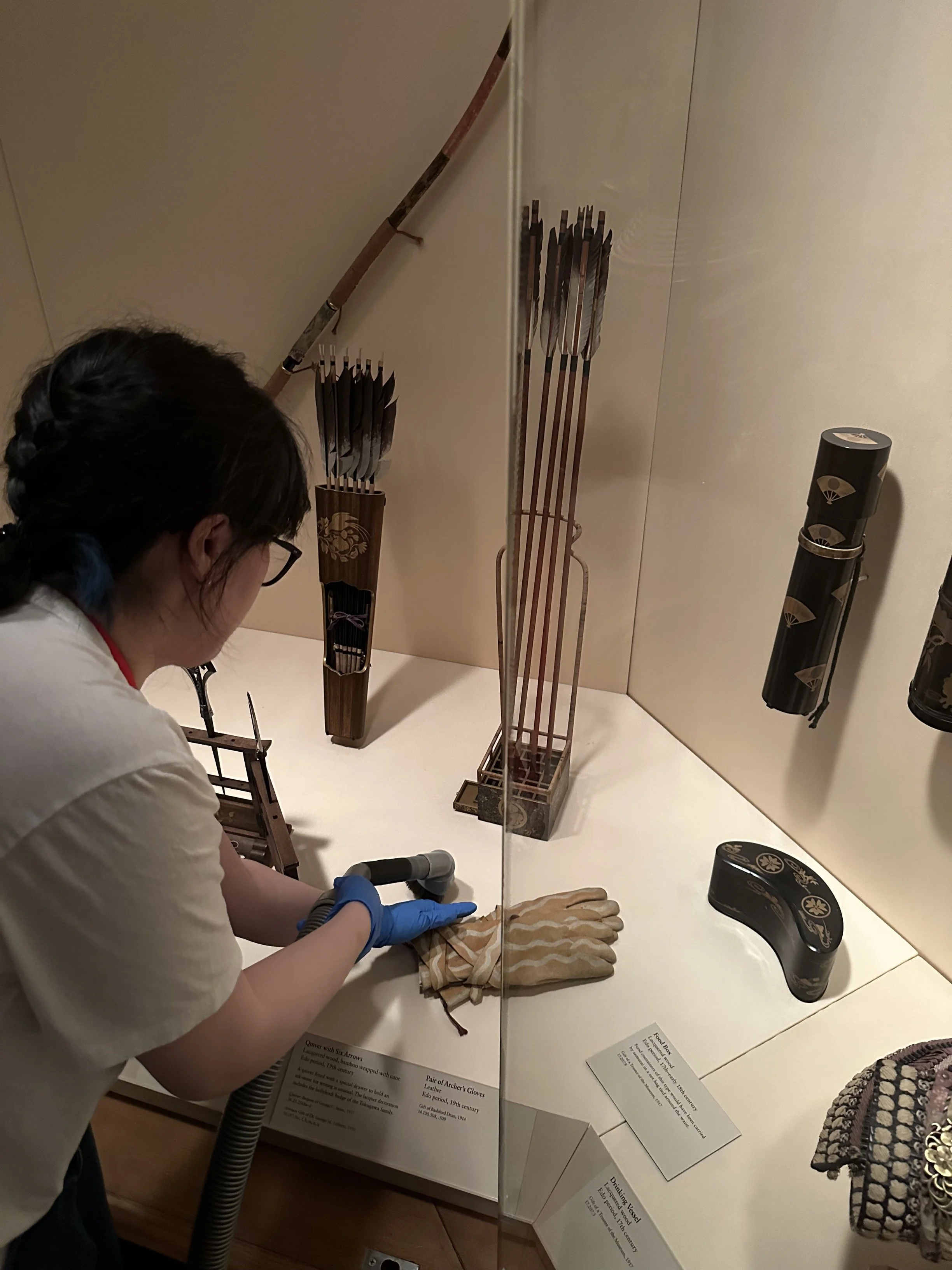 Vacuuming the surface inside of a display case. (Photo: Sean Belair)