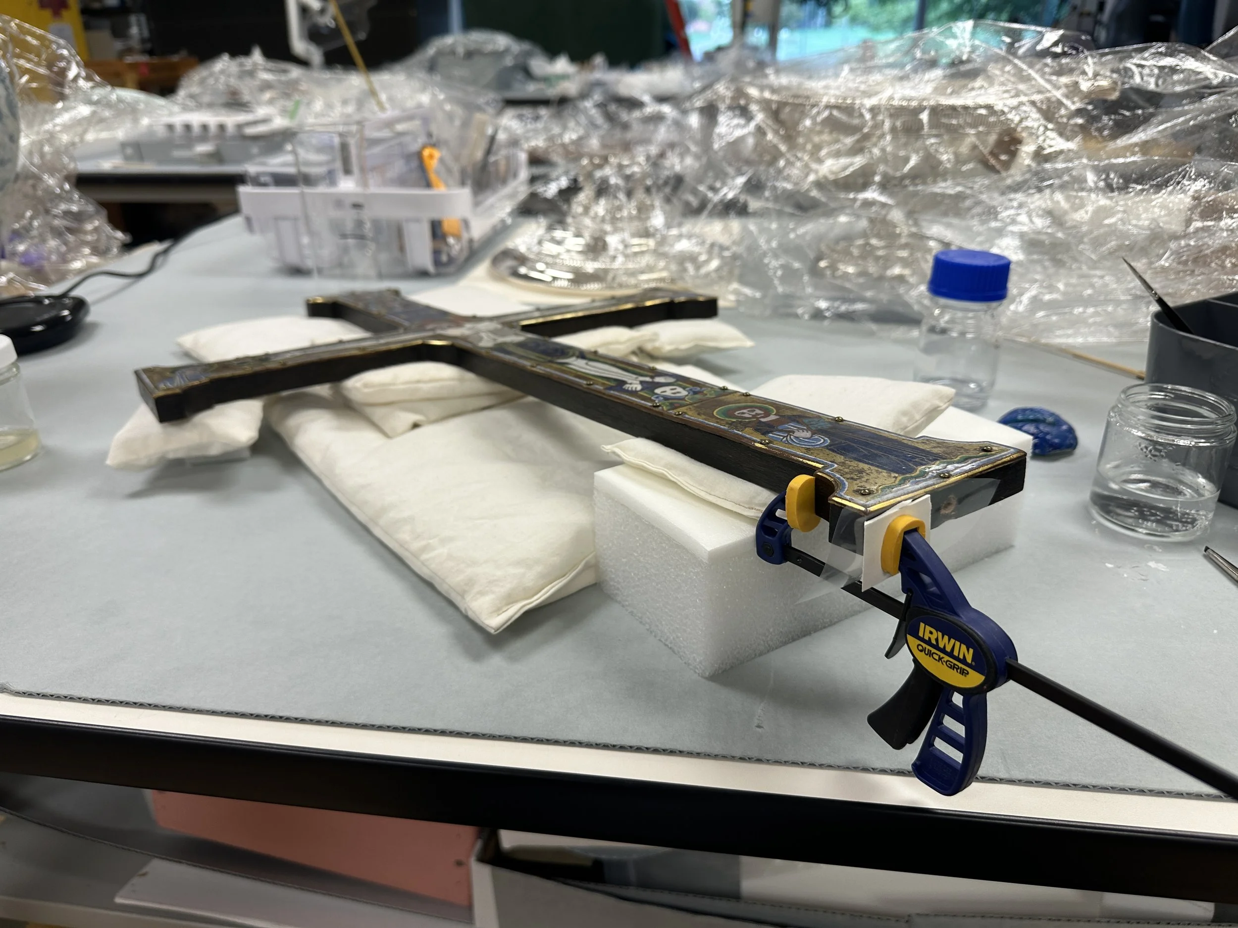 Setup for clamping down the delaminating varnish and wood fibers after wicking in the sturgeon glue, using silicone release Mylar, mat board, and a silicone jaw clamp. (Photo: Jennifer Kim)