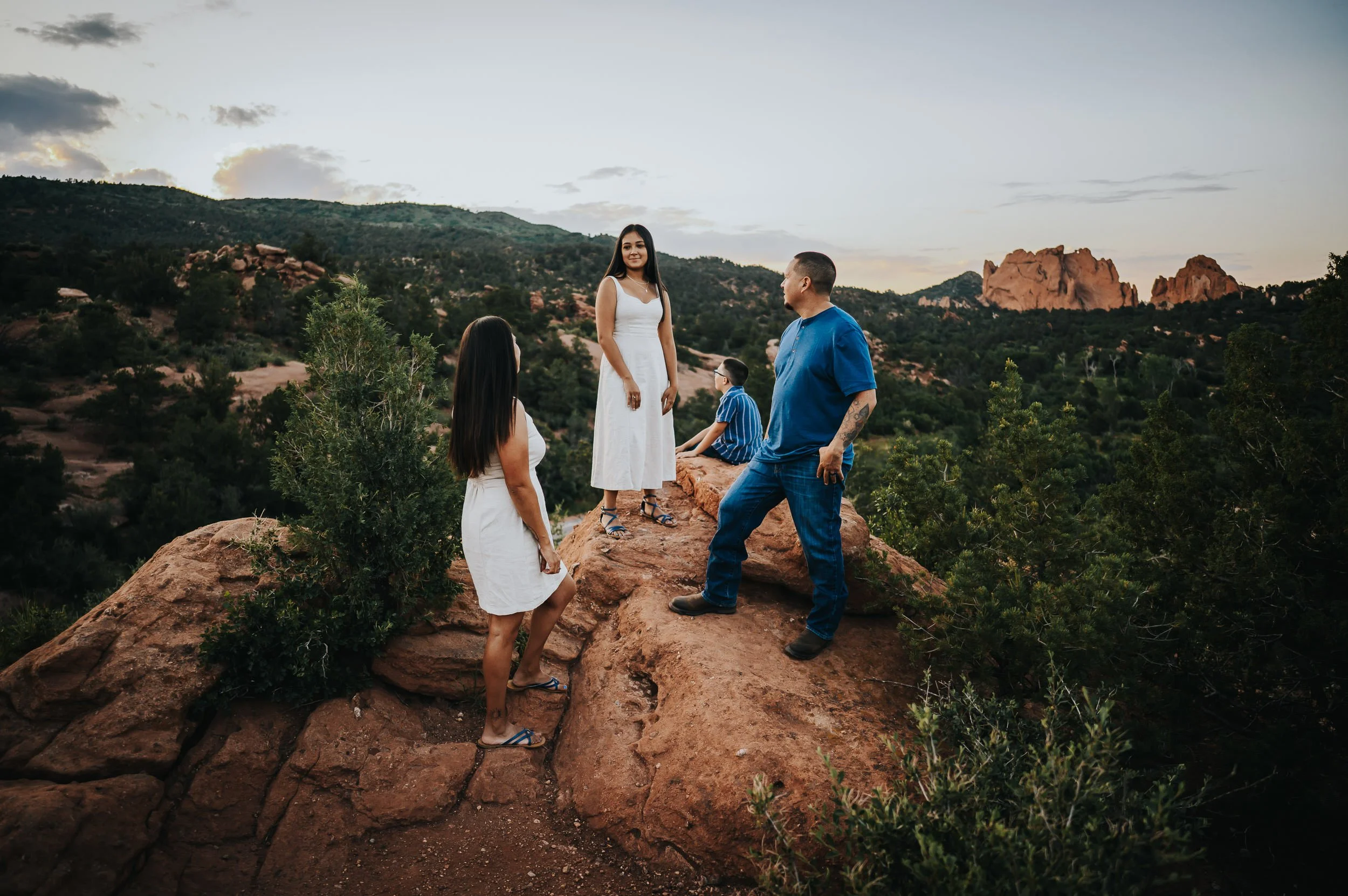 Family of four sitting together on red rocks at Garden of the Gods during golden hour.