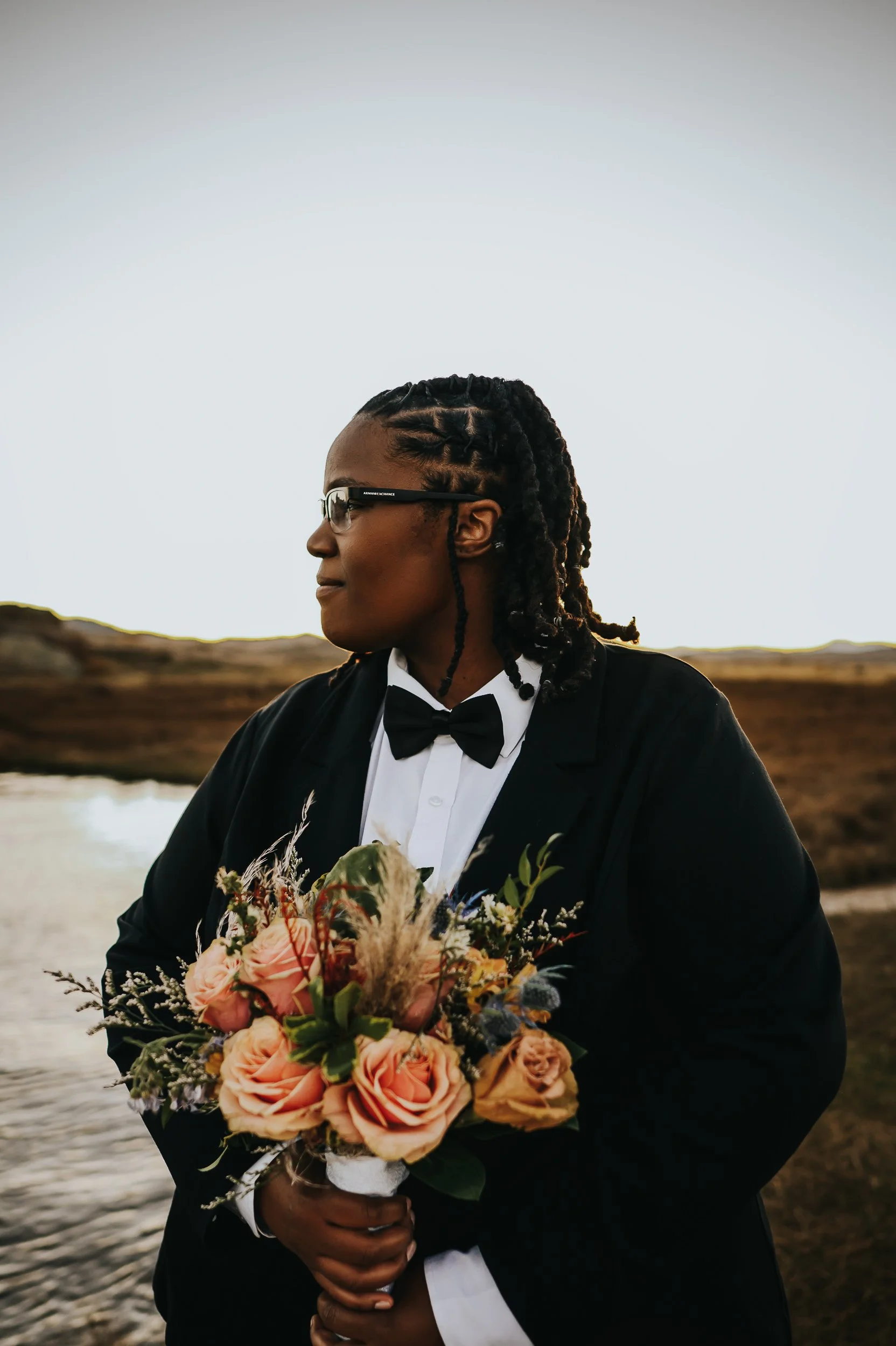 Two brides wandering through golden grasses after exchanging vows.