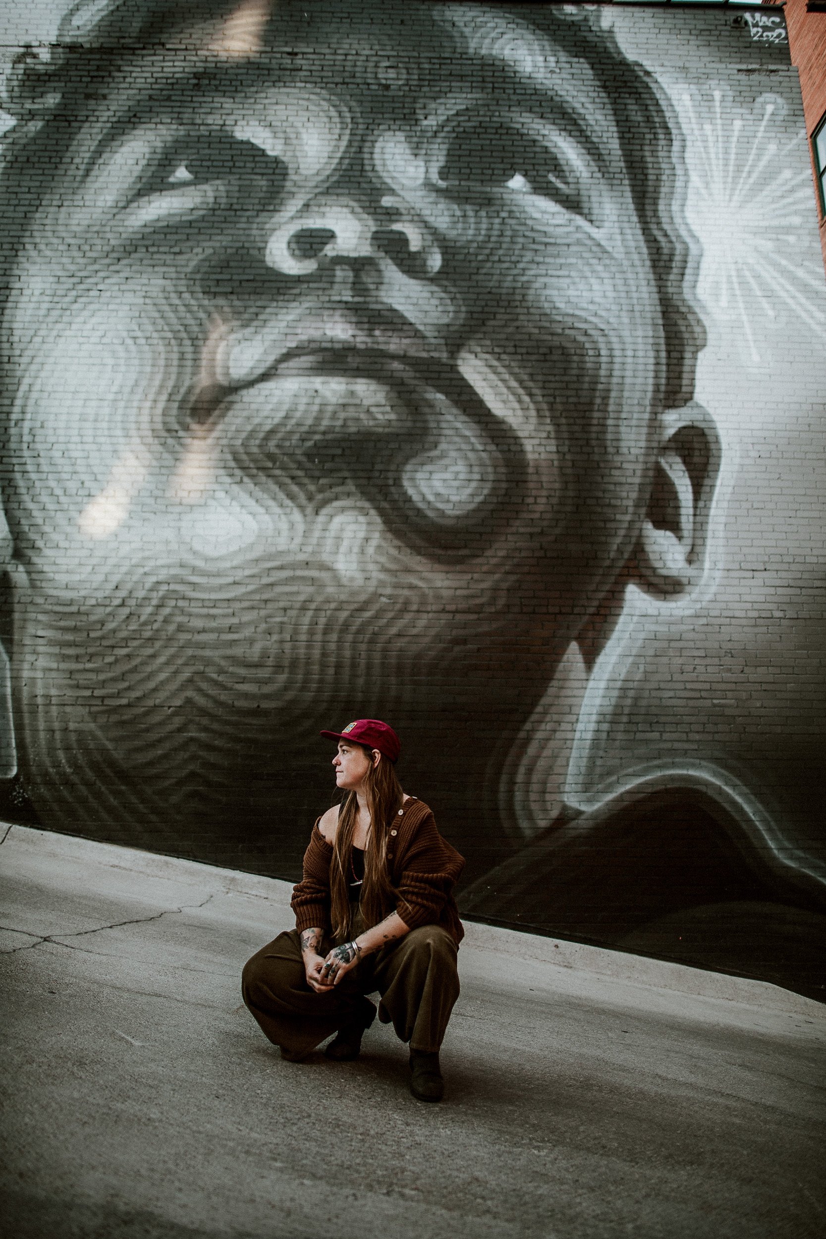 Colorado Springs photographer Sandy Patterson sitting next to a street mural.