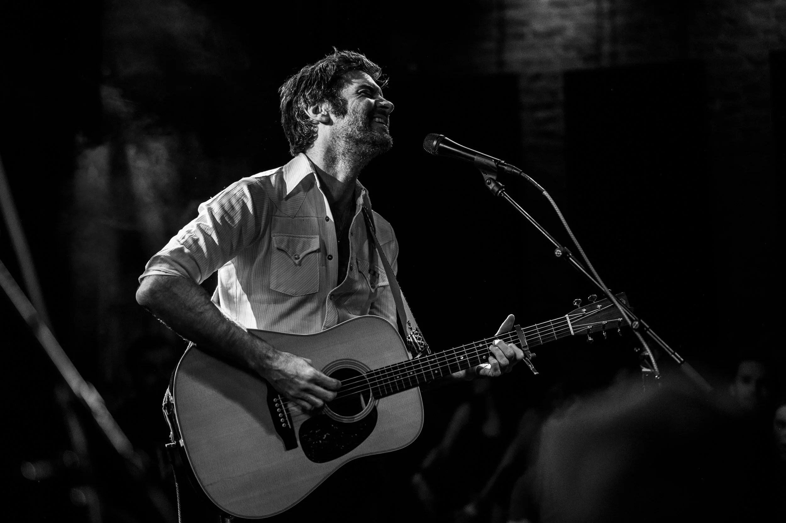 John Craigie illuminated by warm stage lights while performing at The Lariat.