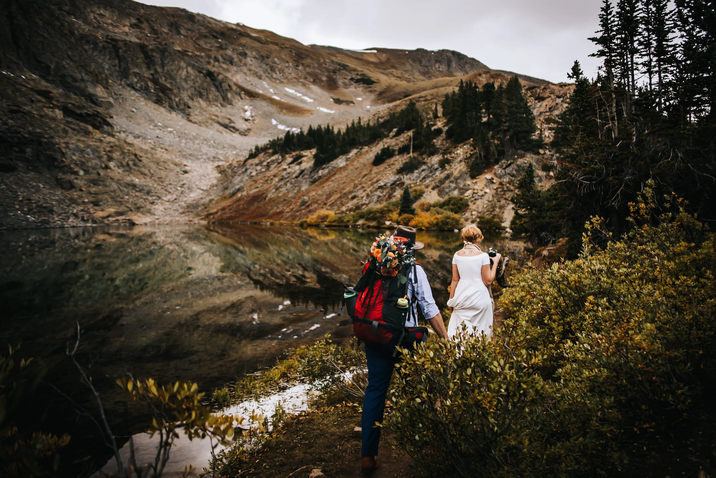 Bride and groom hiking together with backpacks through an alpine landscape at Cottonwood Pass.