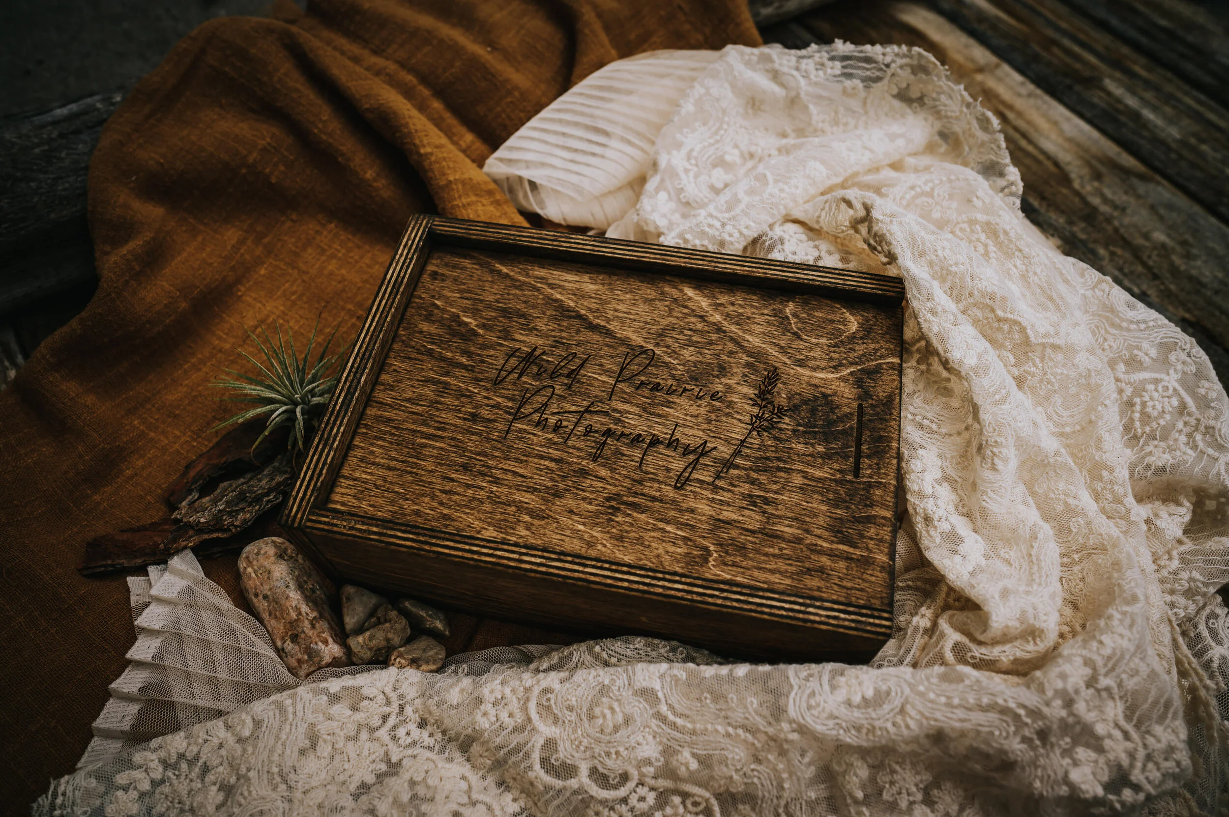 Closed wooden keepsake box with prints resting on burlap fabric.