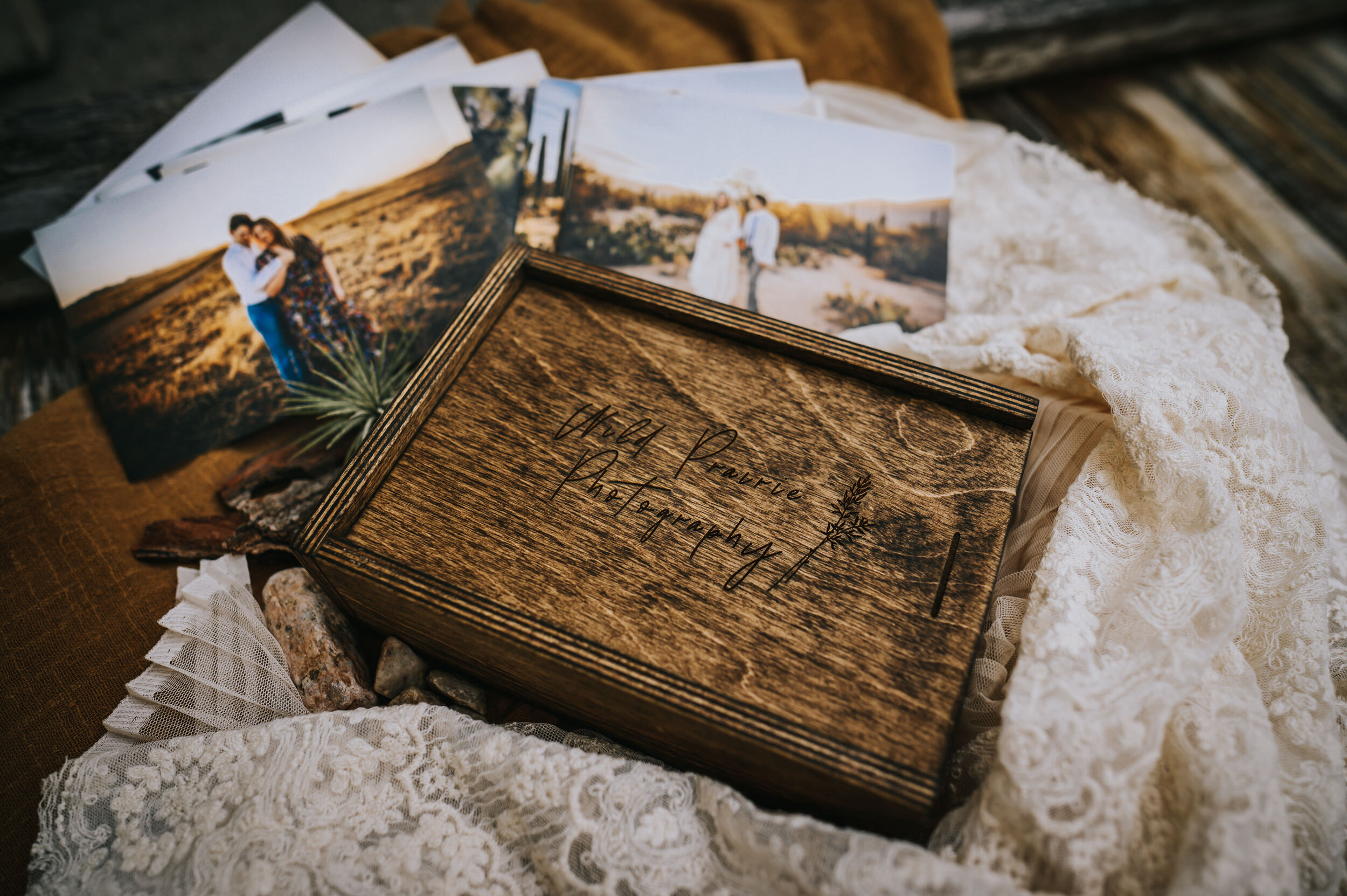 Wooden keepsake box with elopement prints scattered on linen fabric.