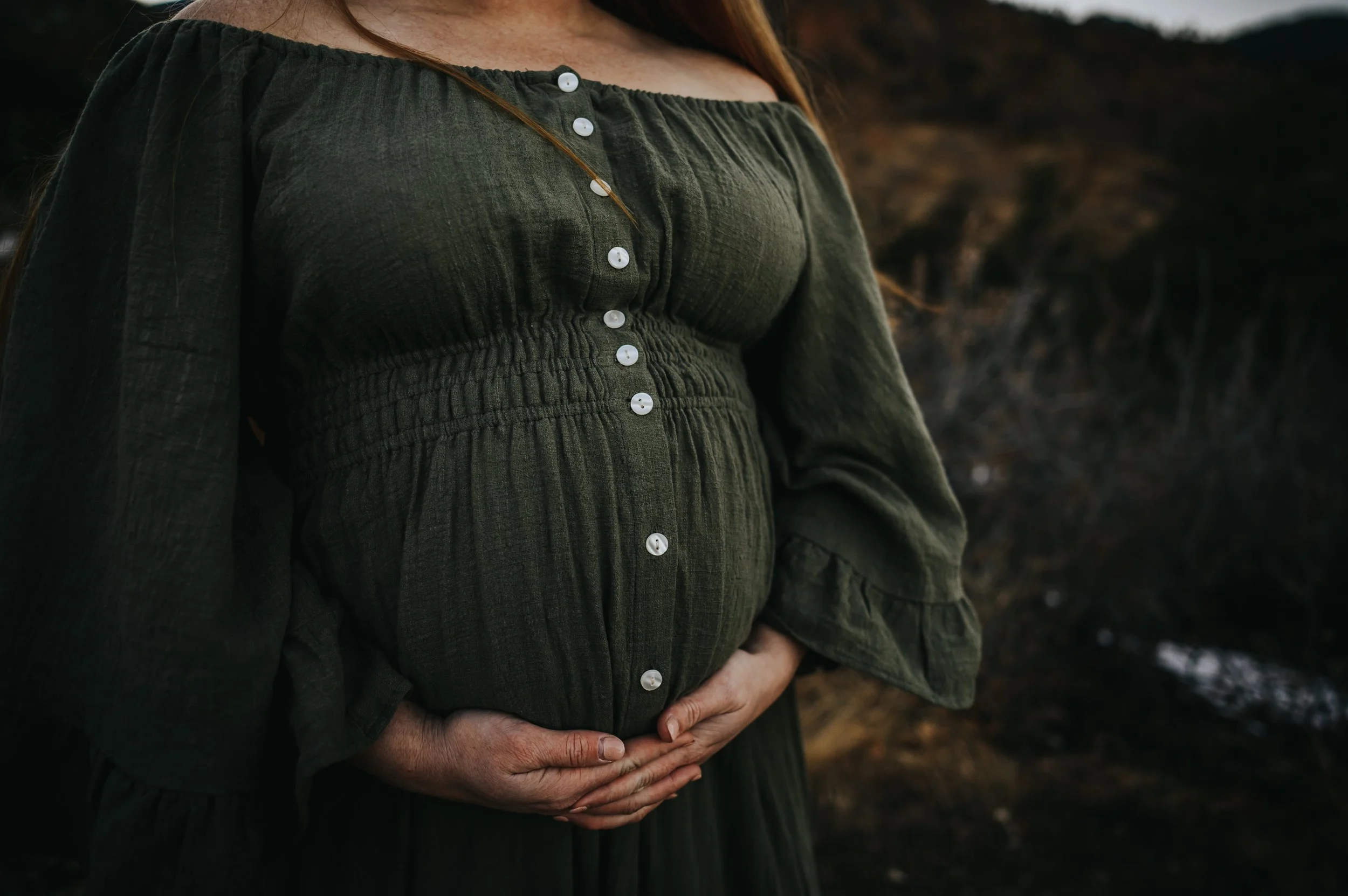 A mother shows off her belly bump during her maternity session in Cheyenne Canon near Colorado Springs.