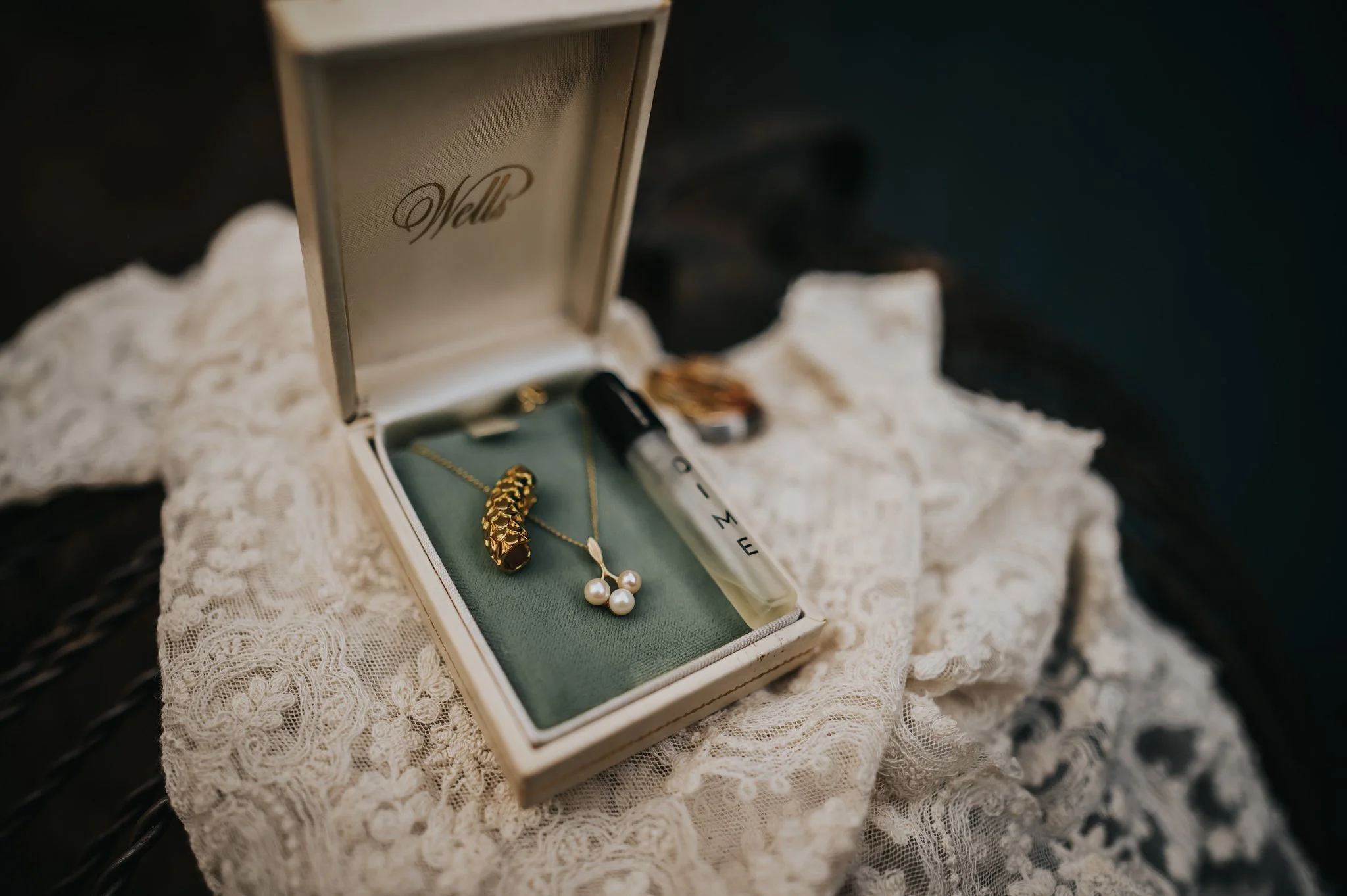 Pearl earrings and necklace in an open jewelry gift box resting on lace fabric.
