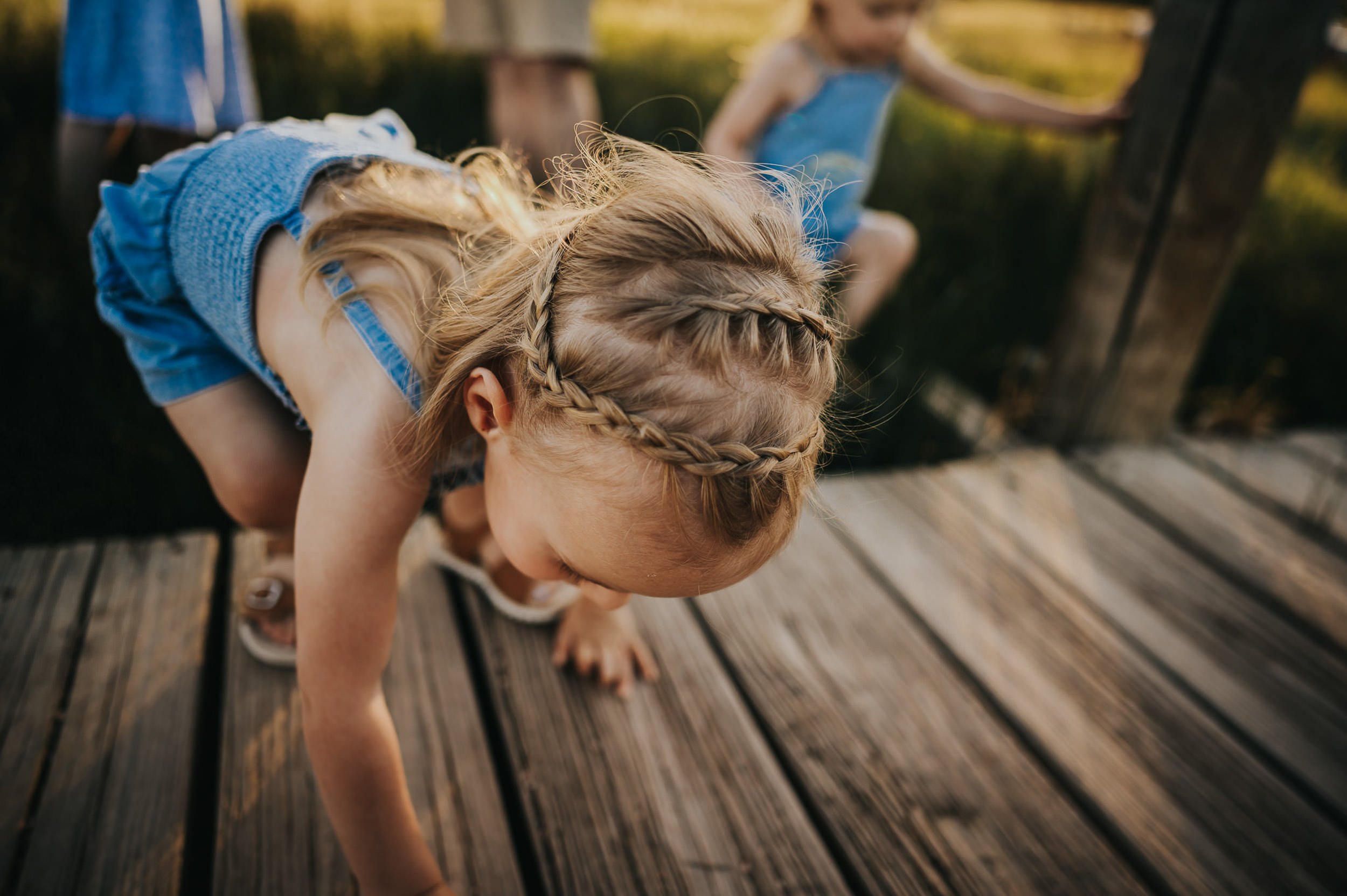 Two sisters lean over the edge of a wooden dock at Ute Valley Park, Colorado Springs.