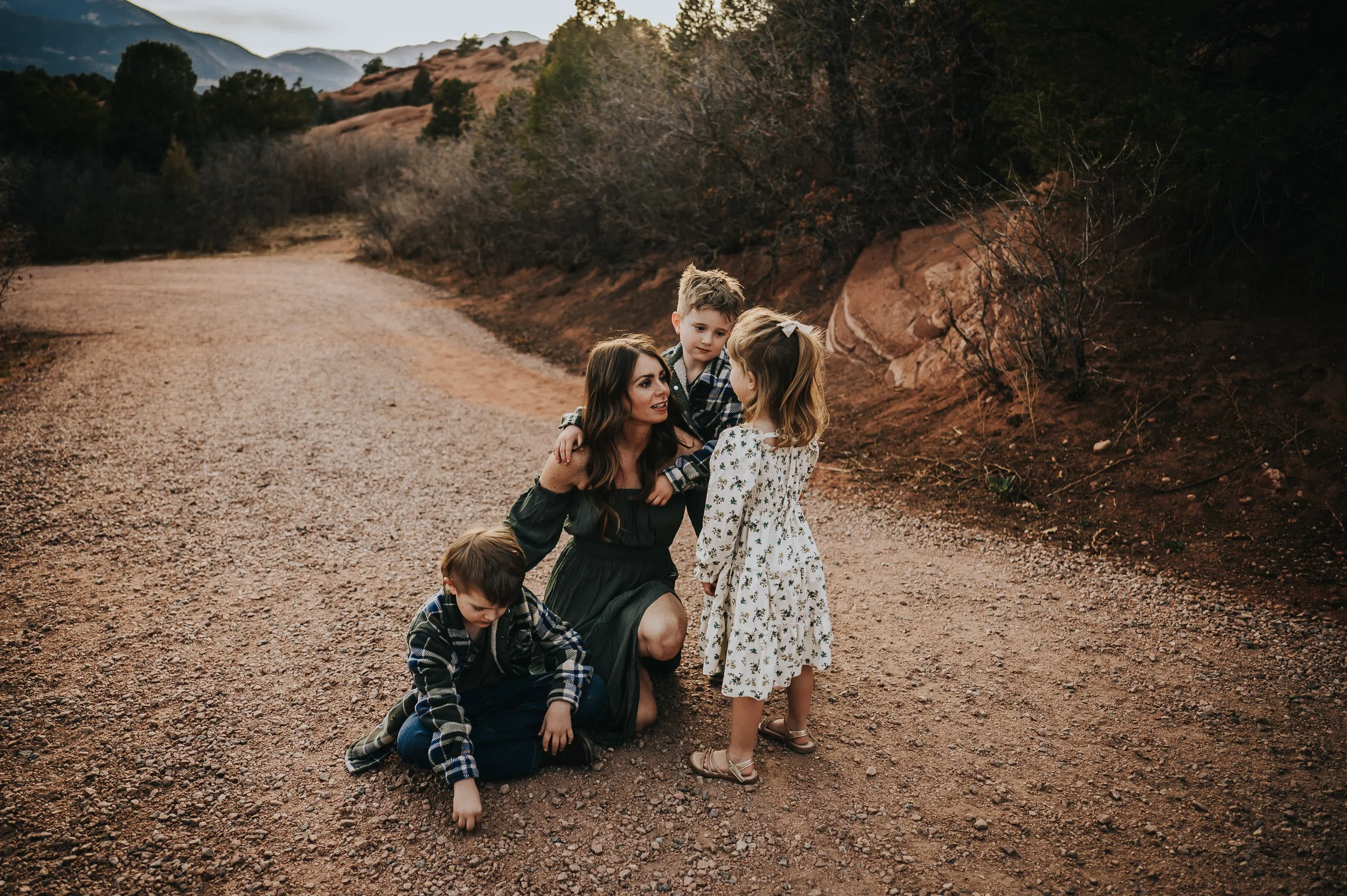 Mom crouching down with all three kids gathered around her.