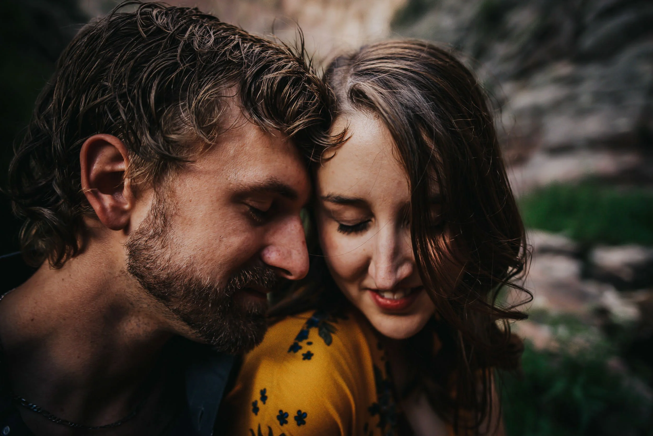 A couple leans together in a tender closeup, faces nearly touching, warm moody light.