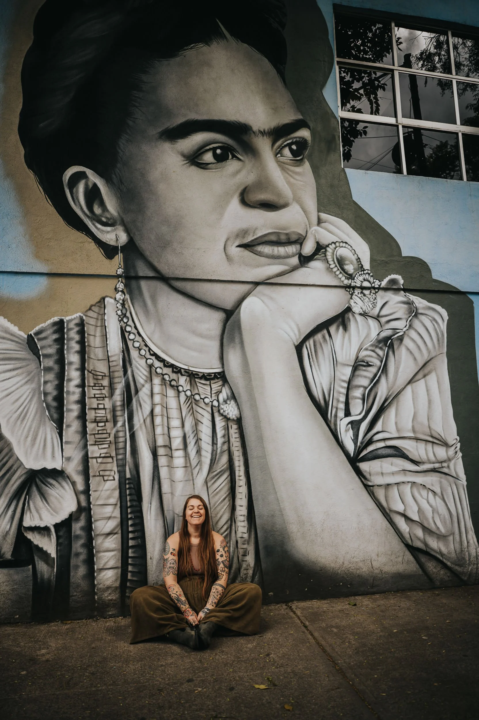 Sandy, Colorado Springs photographer, seated in front of a large Frida Kahlo mural.