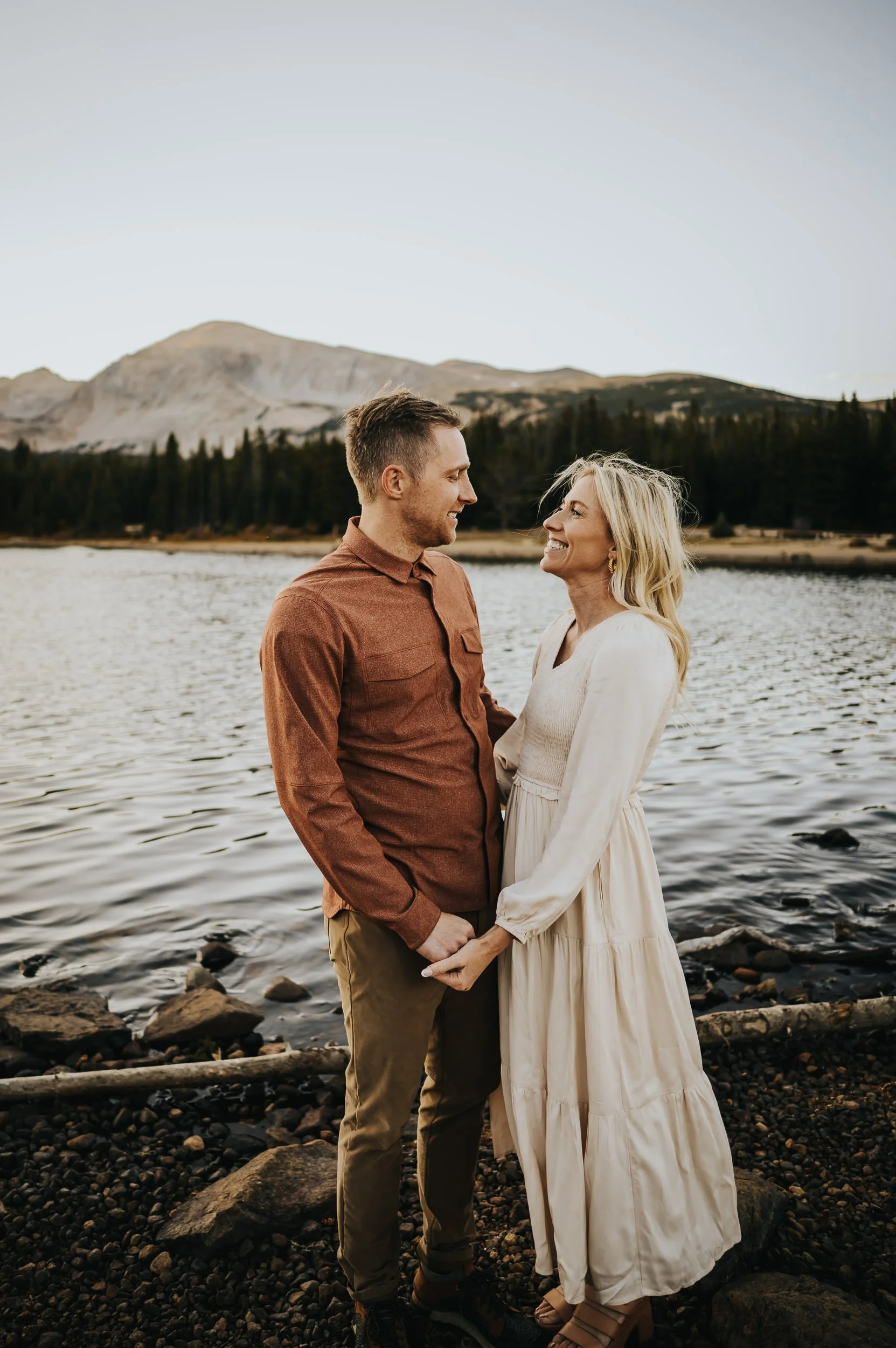 Family gathered by the water at Brainard Lake as the sun sets behind the mountains.