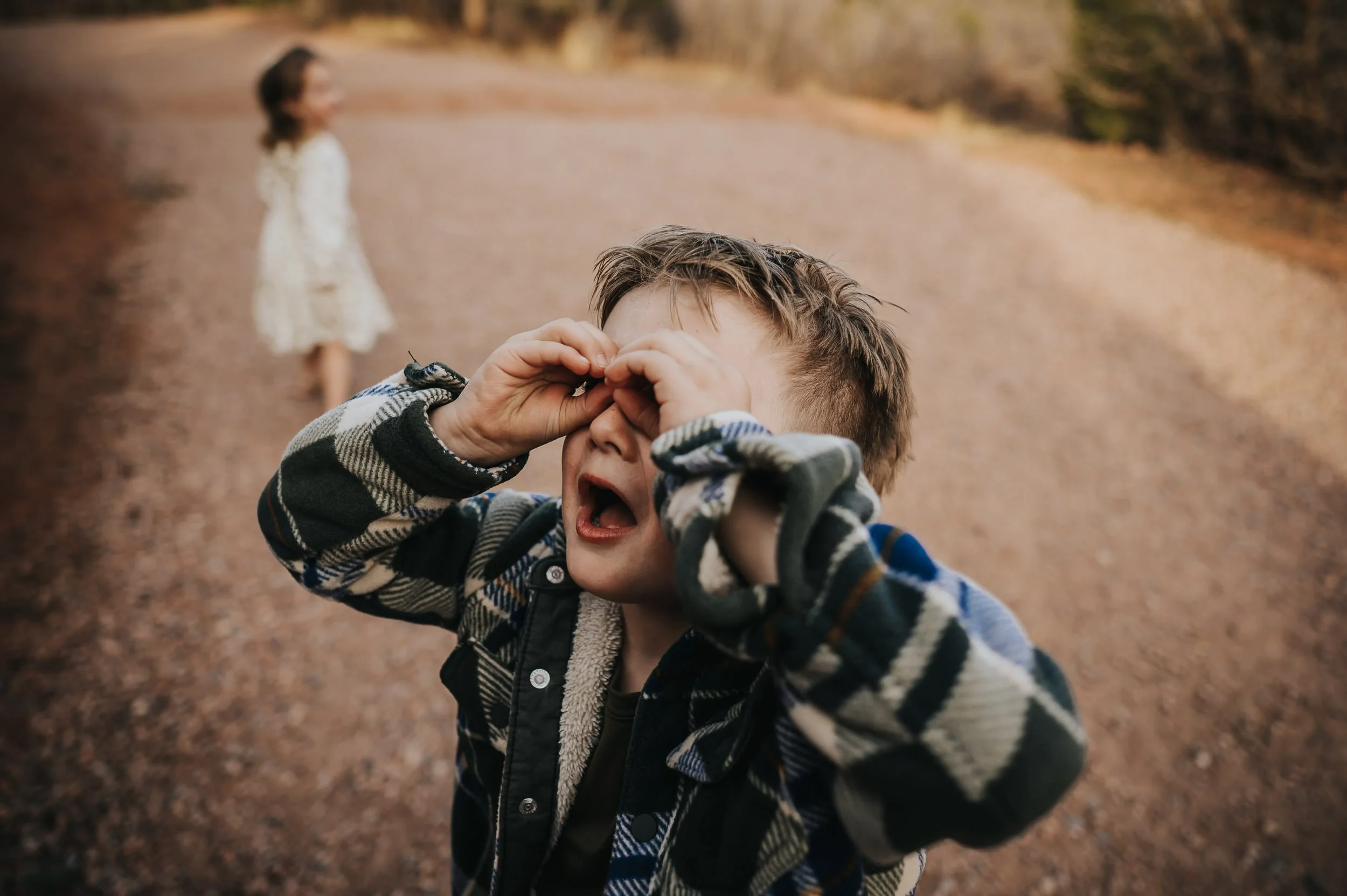 Close-up of a boy making a silly face with his hands near his cheeks.