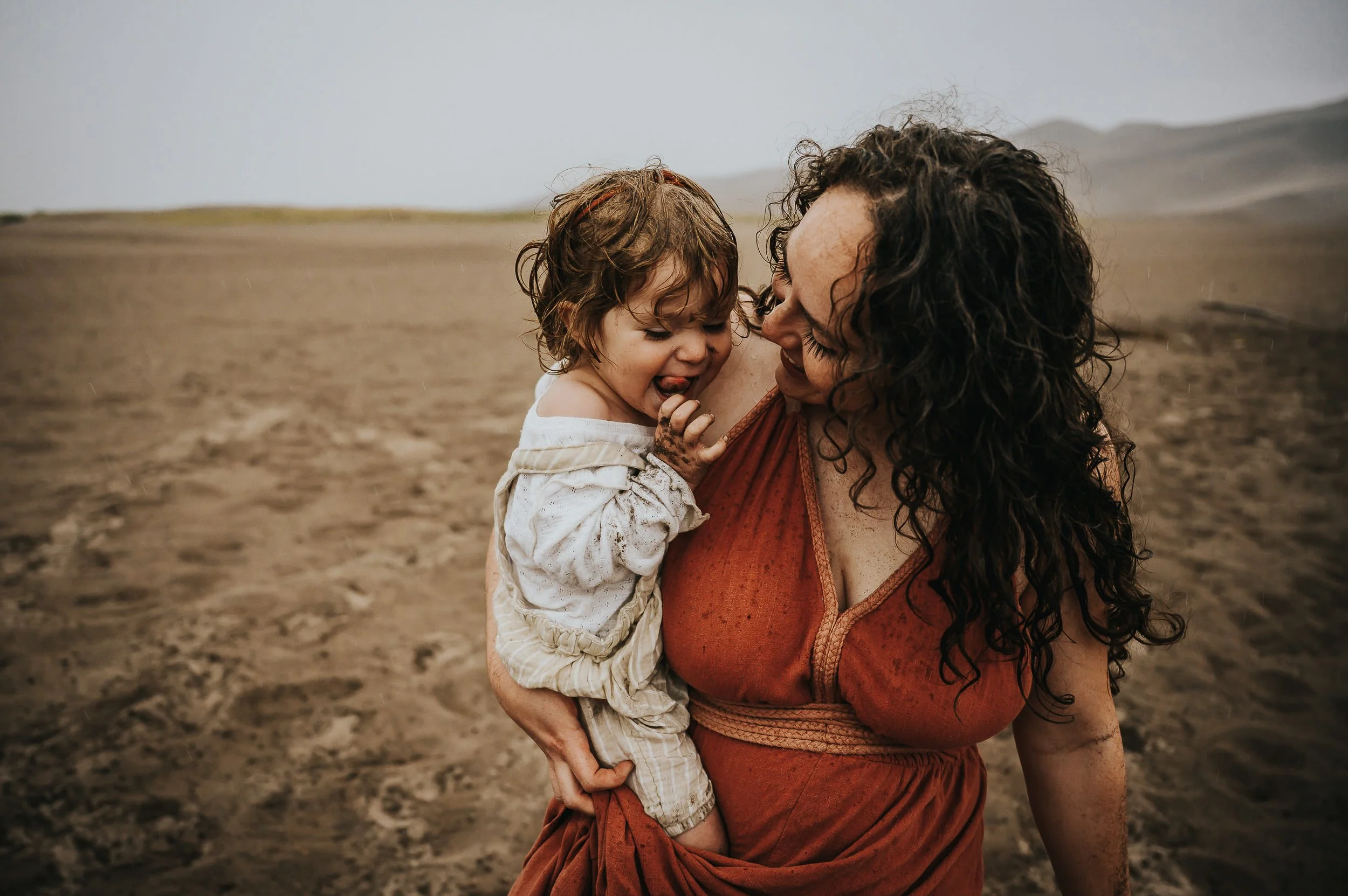 Mom and young daughter in tender close-up moment, noses touching, warm earth tones.