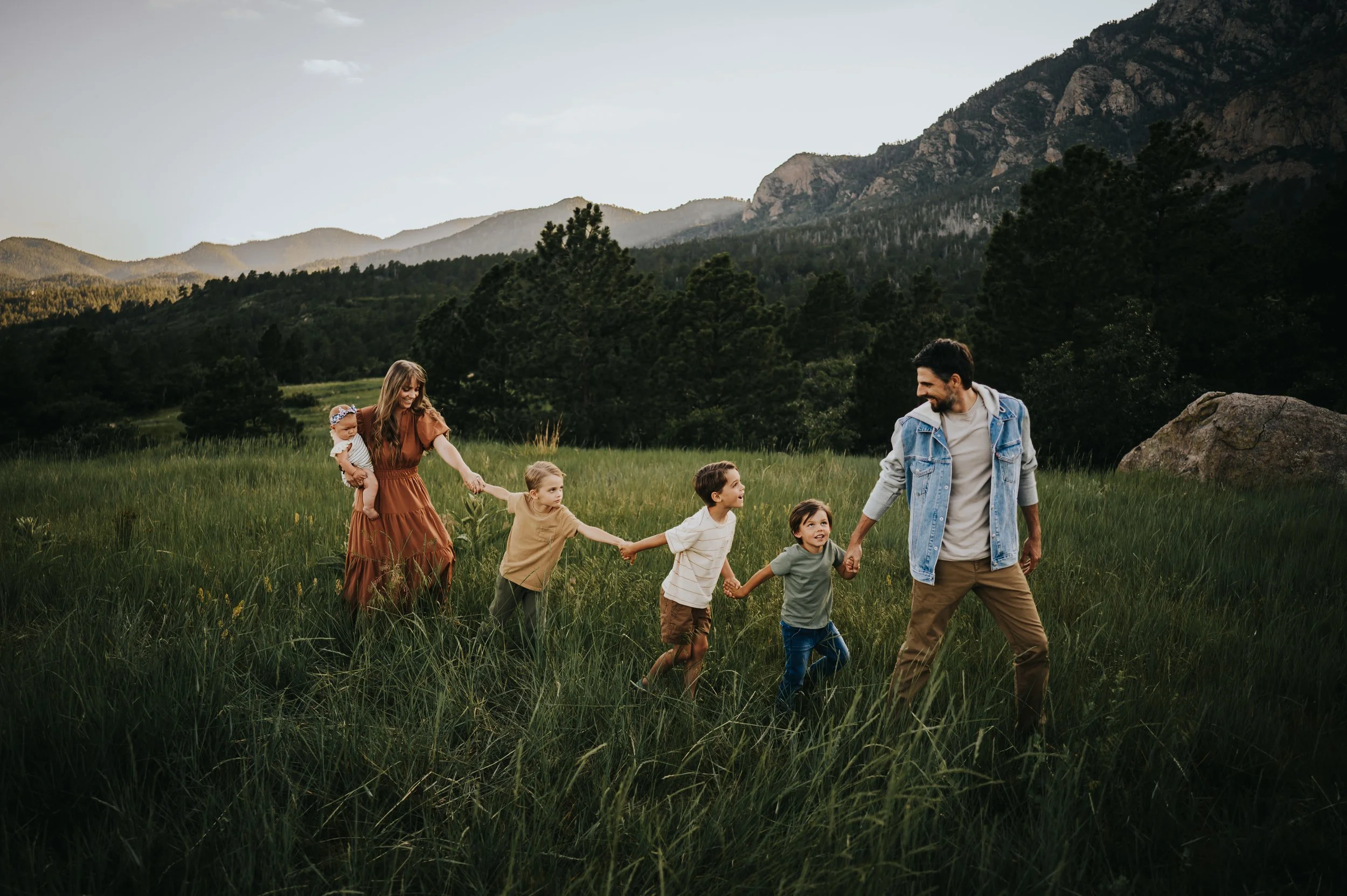 Family in fall colors at Cheyenne Mountain State Park with prairie grass and mountain backdrop.