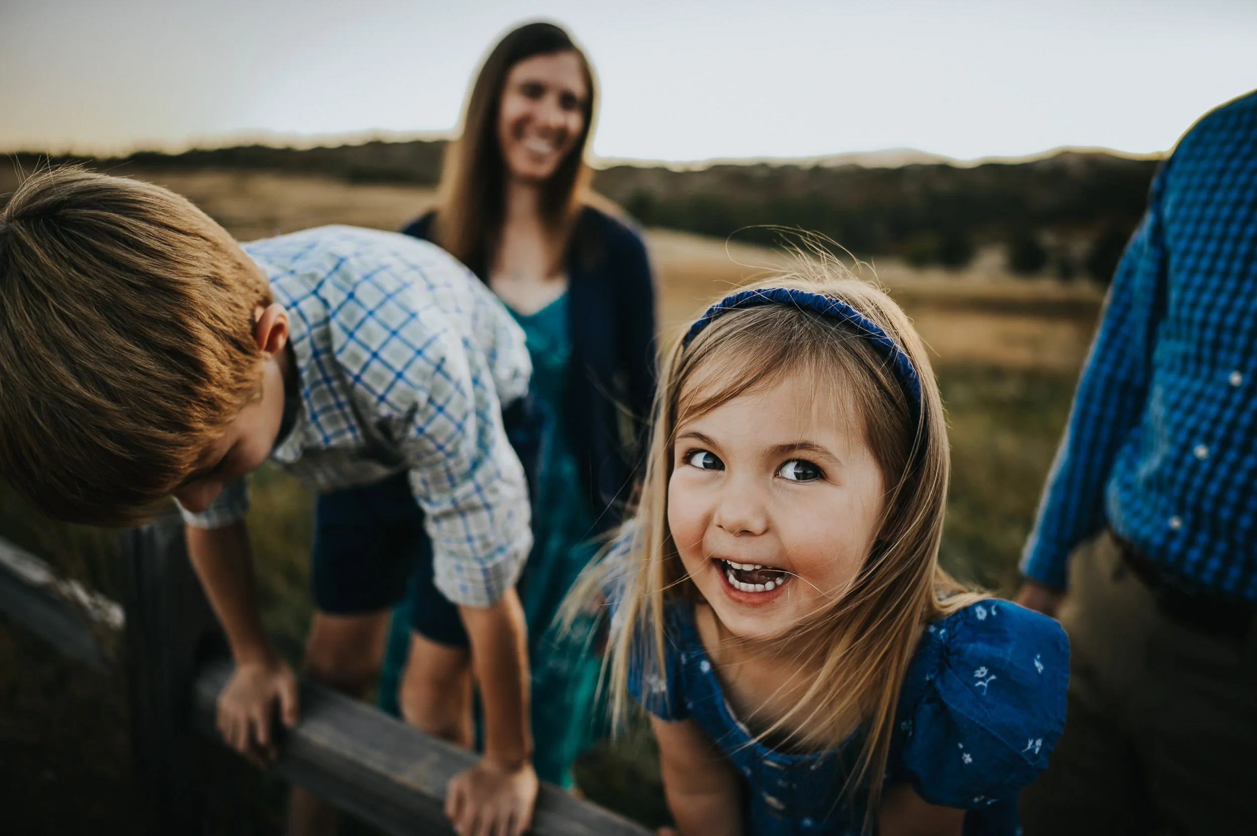 A brother and sister climb on a wooden fence and laugh with joy at Ute Valley.