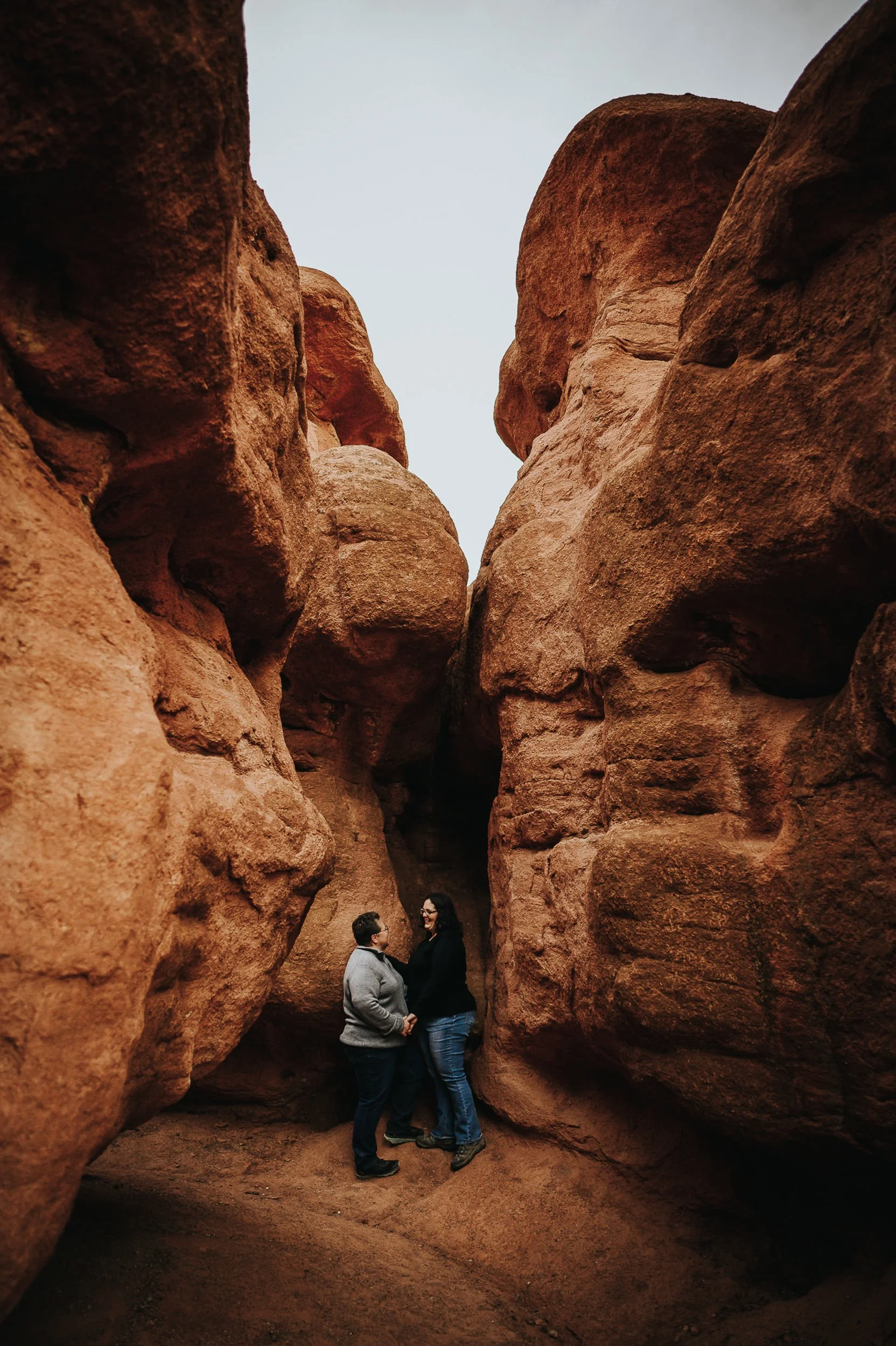 A couple embraces between towering red rock formations at Garden of the Gods.