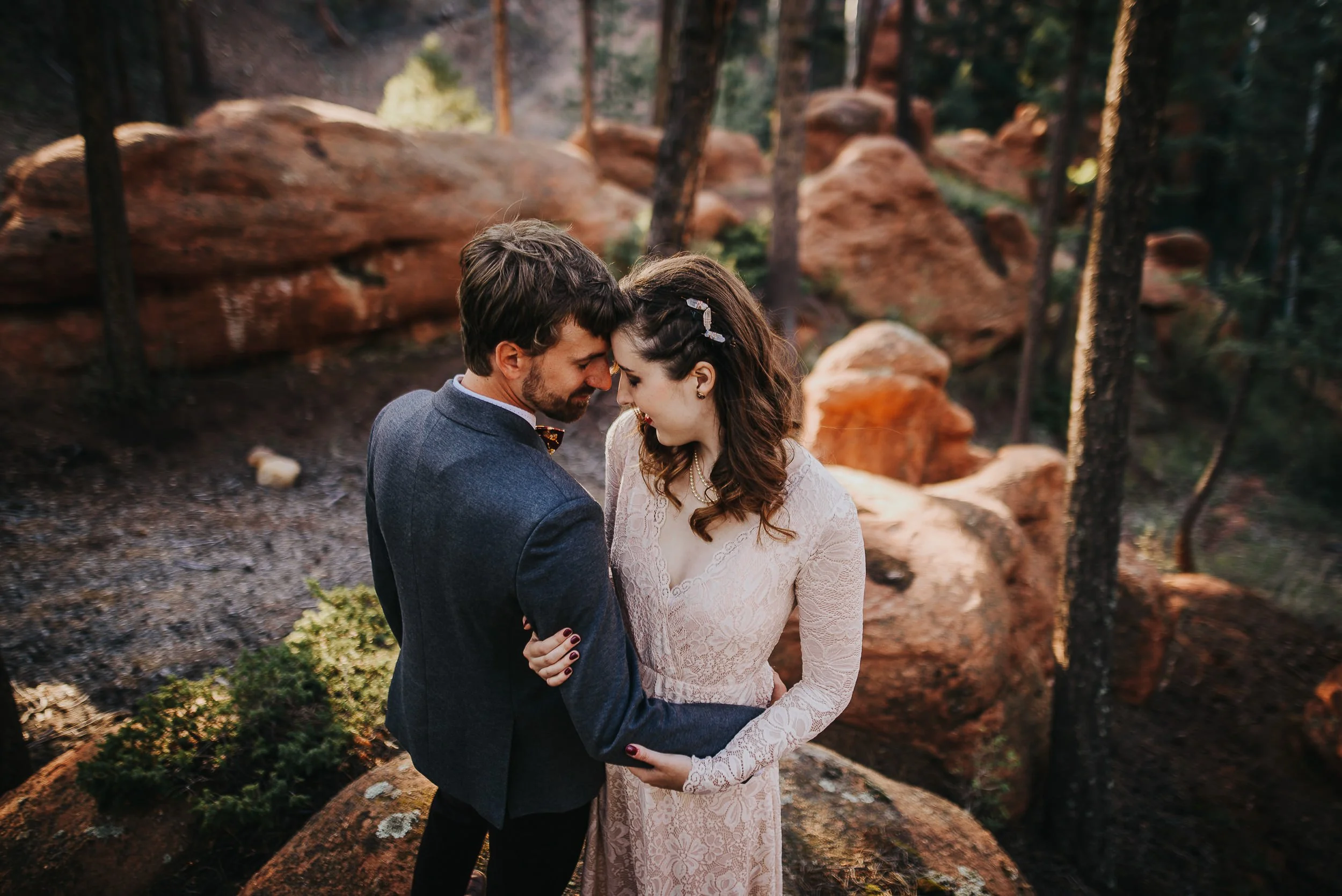 A bride and groom share a forehead-to-forehead moment among red rock formations in Woodland Park, Colorado.