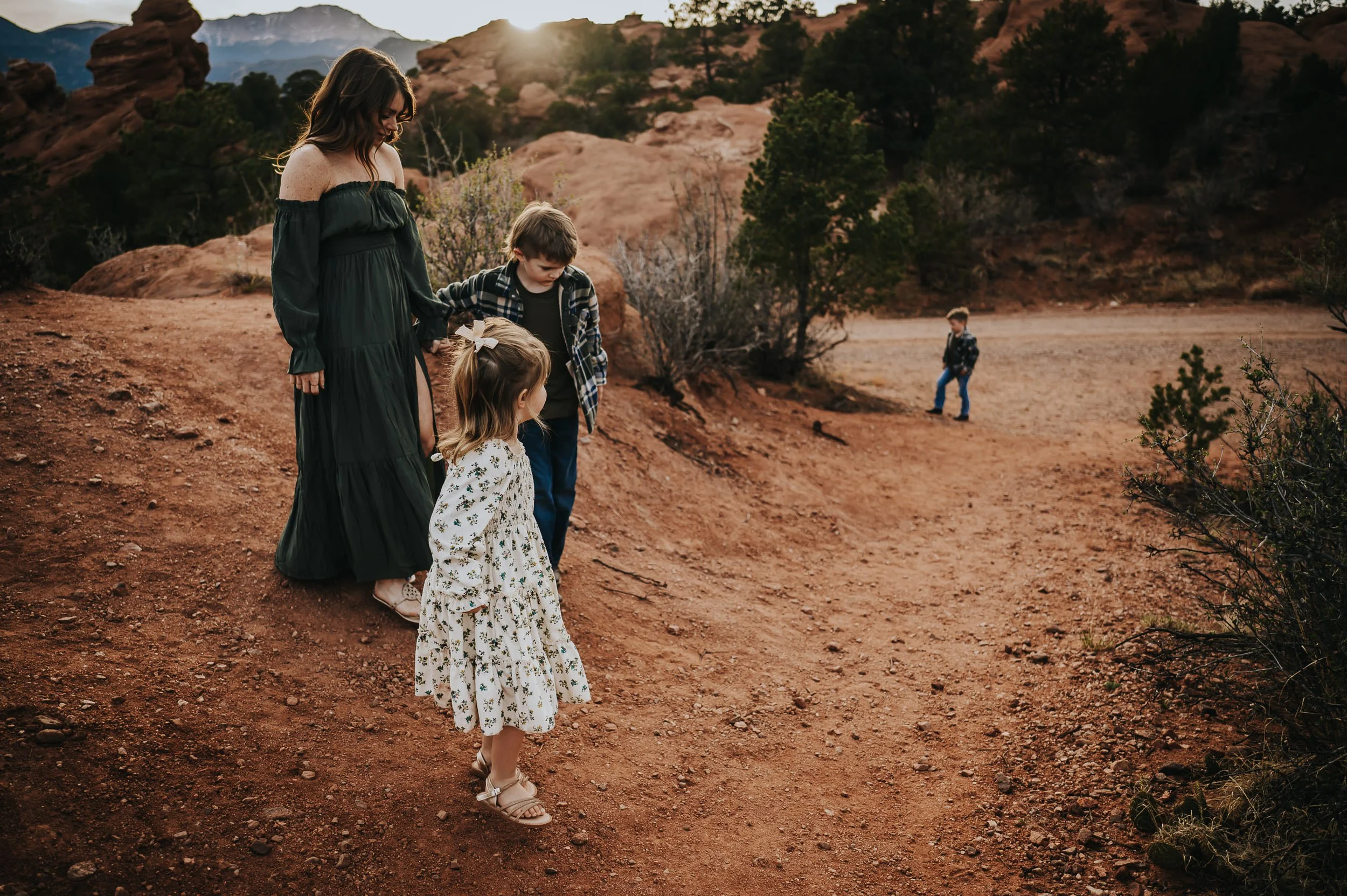 Mother and three kids standing together on a dirt path with Pikes Peak in the distance.