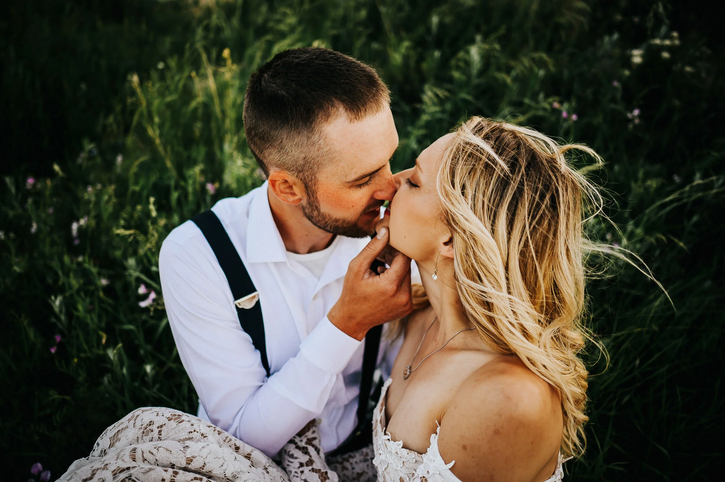 A couple nearly kisses in a lush green Colorado summer landscape, foreheads together, soft and close.