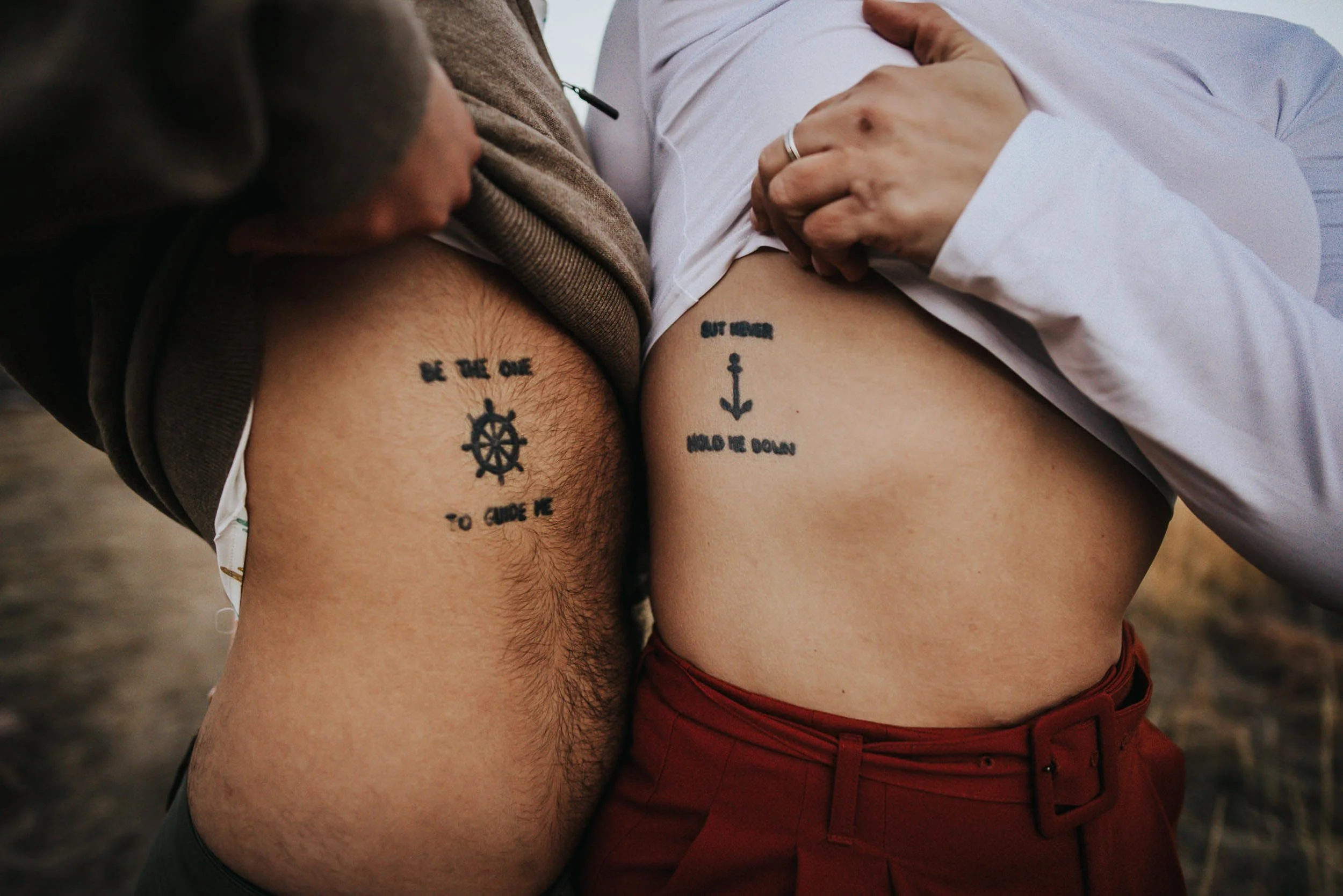 A closeup of two people's matching tattoos side by side, hands resting together.