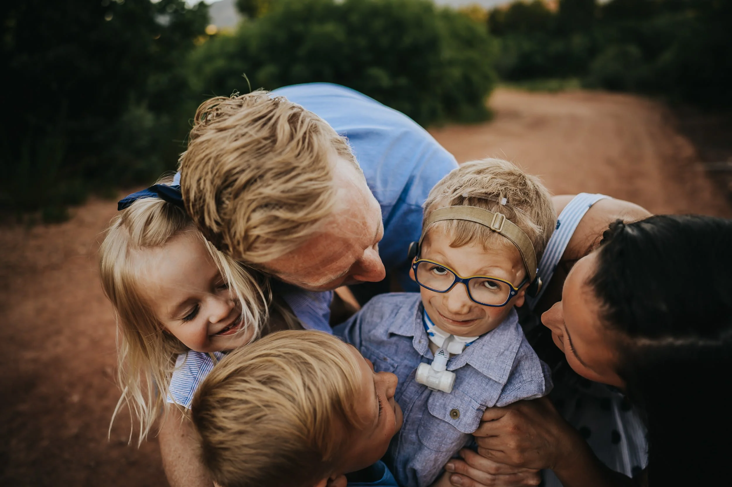 A family stands together in a wide Colorado landscape under an overcast sky, mountains behind.