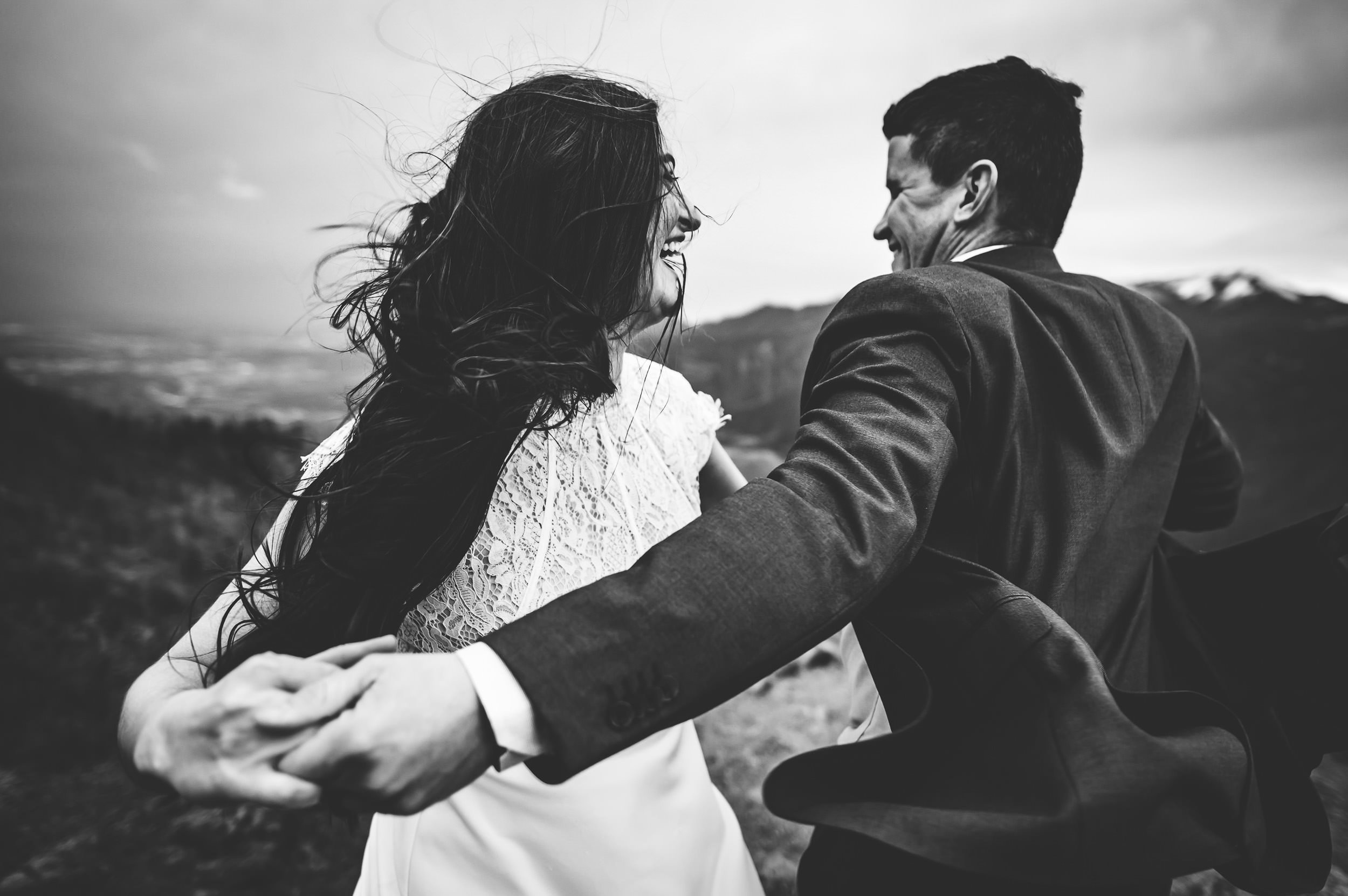 A couple dances close together in a black and white portrait, wind in her hair, his hand on her waist.