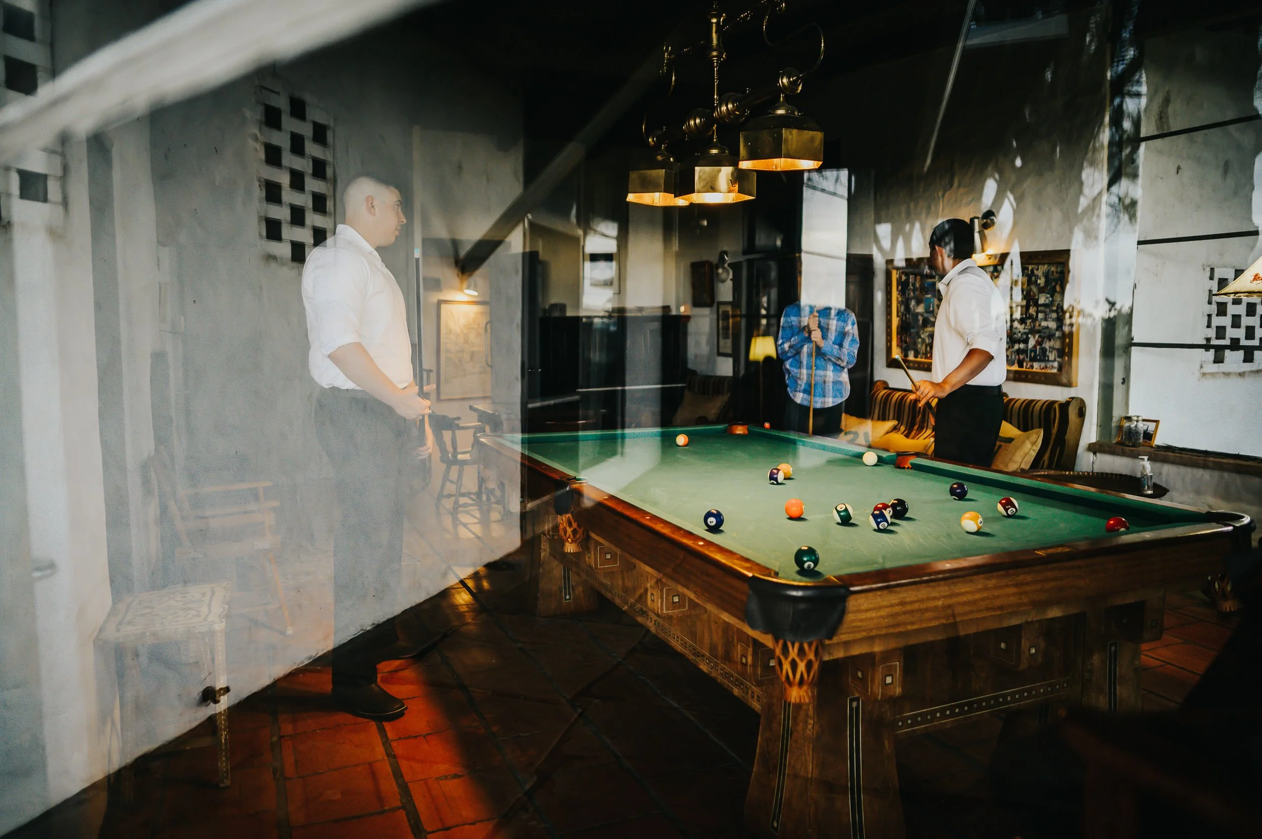 A couple shares a moment inside a moody indoor venue with a pool table in the background.