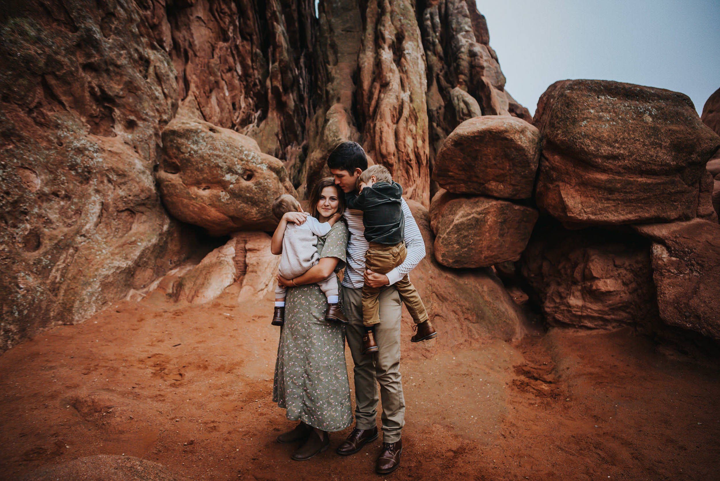 Father and mother holding their children among red rock formations.