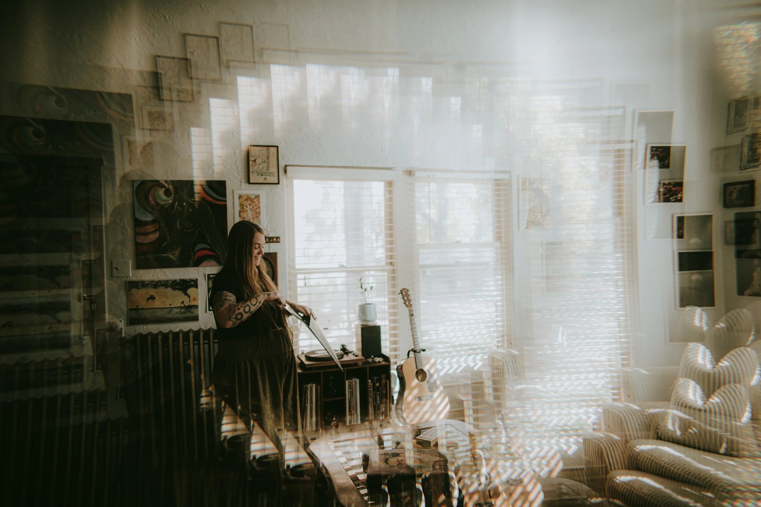 Sandy, Colorado Springs wedding photographer, sitting in a warmly lit room with natural window light and a guitar nearby.