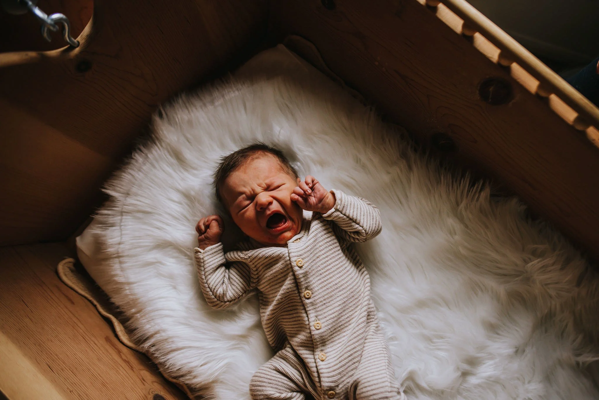 Newborn baby sleeping peacefully in a wooden cradle during a lifestyle newborn photography session in Colorado Springs.