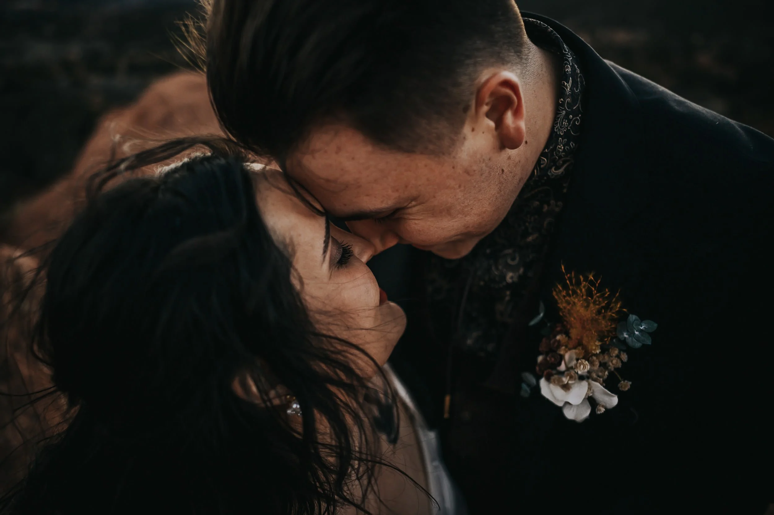 A couple presses foreheads together in an intimate closeup, he wears a boutonniere.