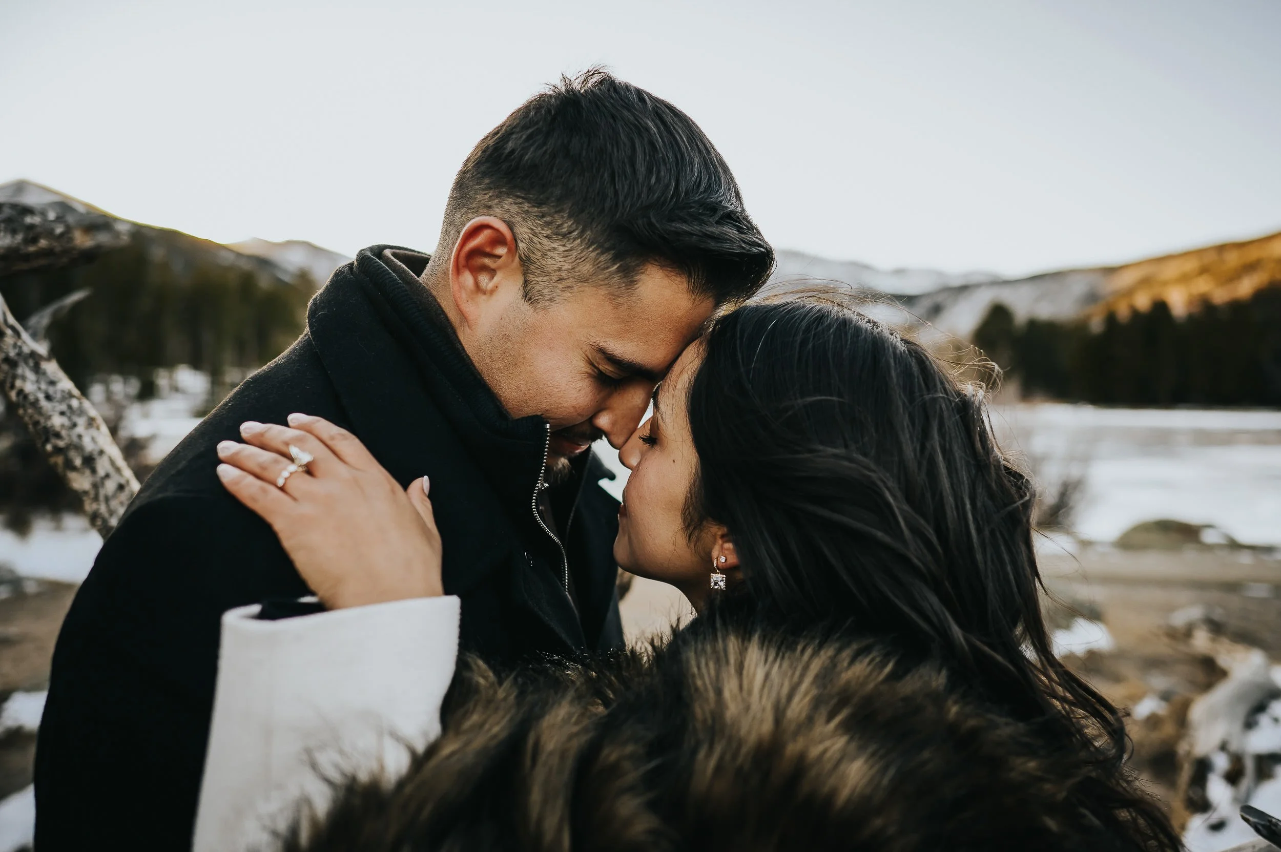 A couple leans forehead to forehead in a tender closeup, wrapped in a fur blanket after their marriage proposal session.