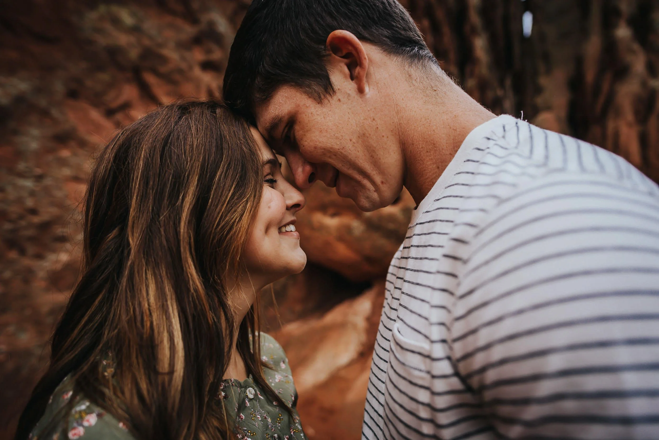 A couple leans forehead to forehead in a tender closeup, he in a striped shirt.