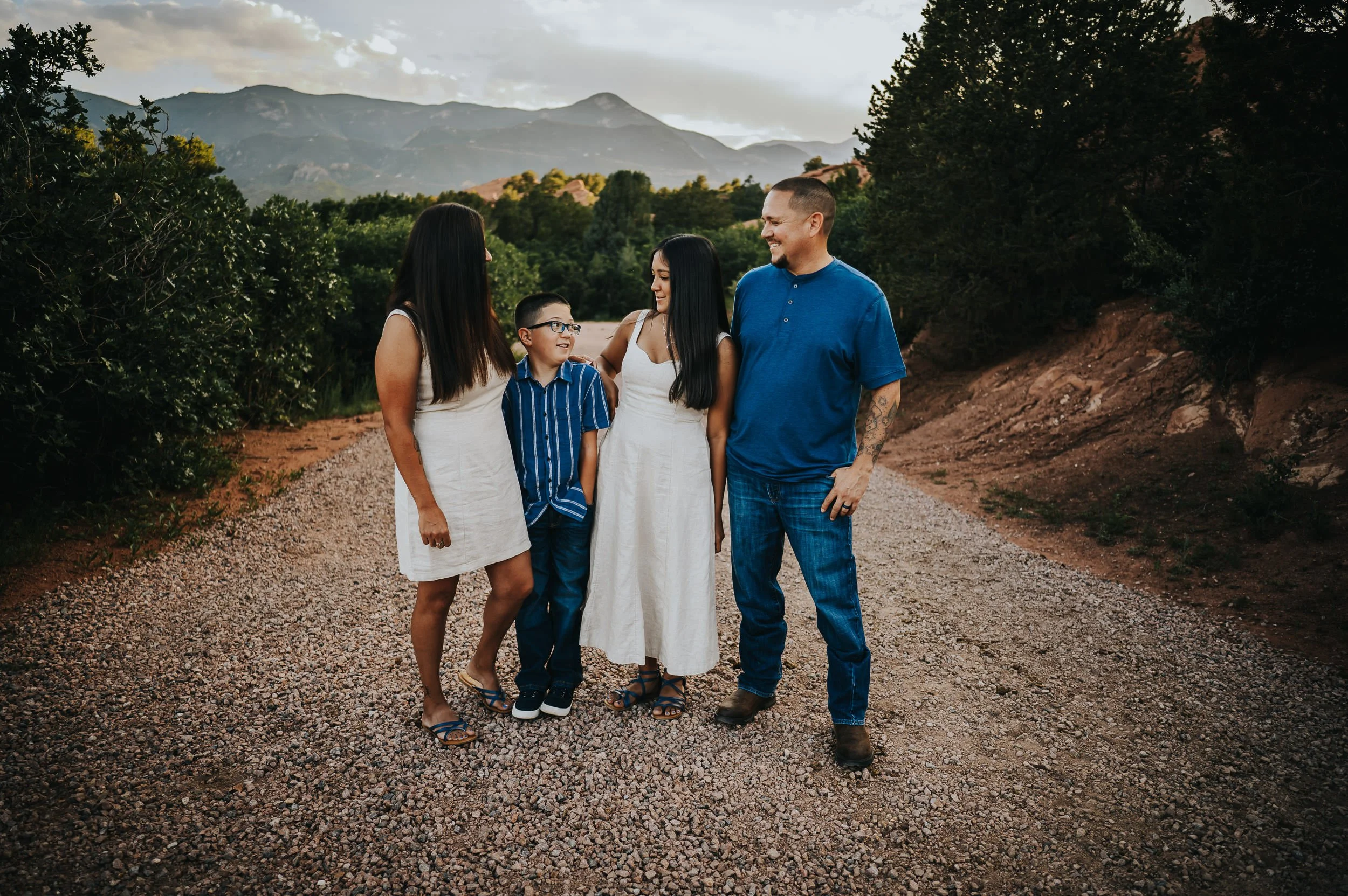 Family walking hand in hand along a sunlit trail at Garden of the Gods with red sandstone towers.