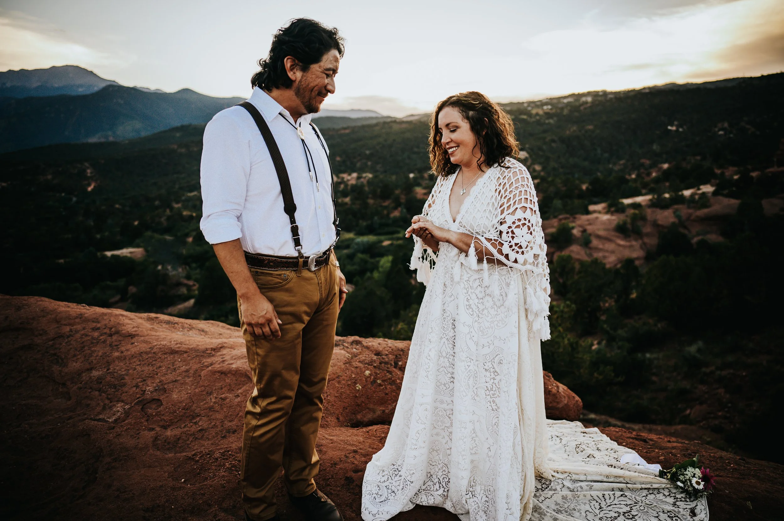 Couple laughing together at Garden of the Gods at golden hour, bride in a lace boho dress.