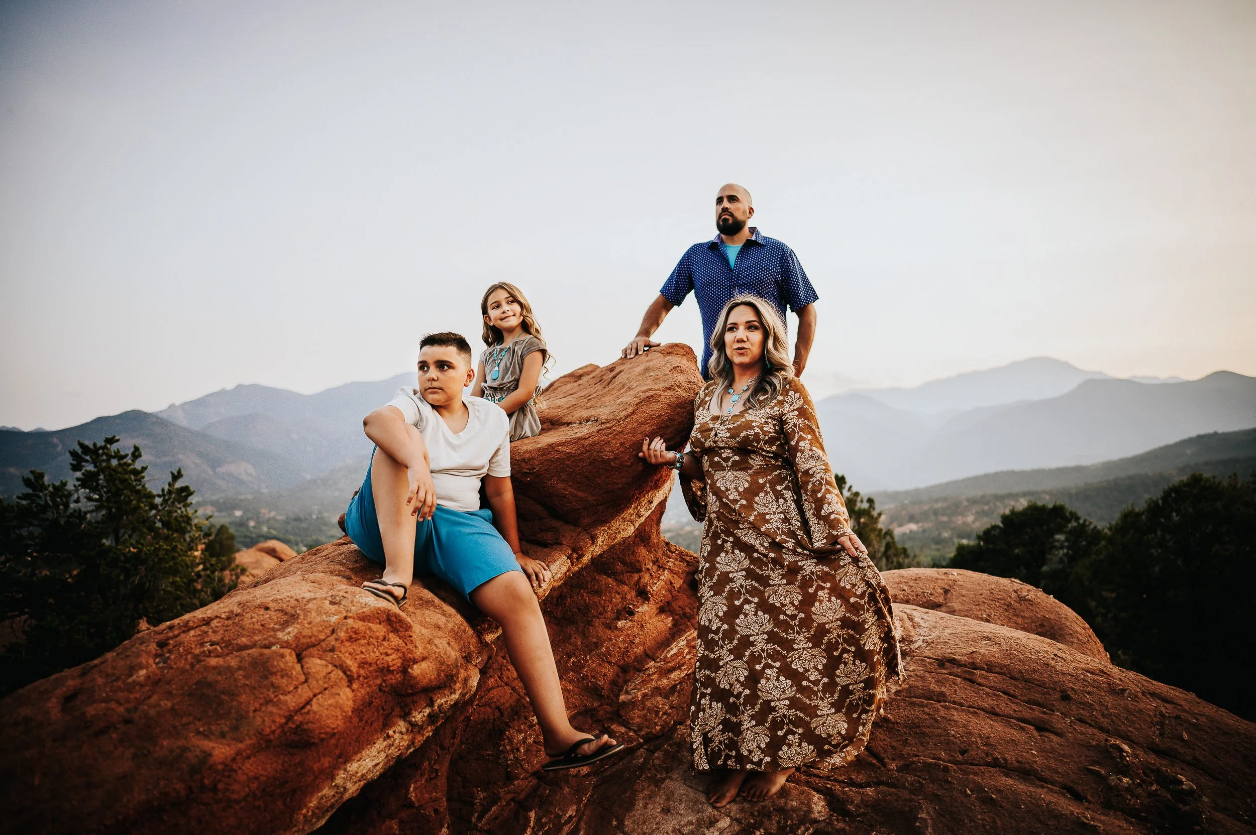 Family of three walking at Garden of the Gods, coordinated in blue and cream outfits that contrast with the red rocks.