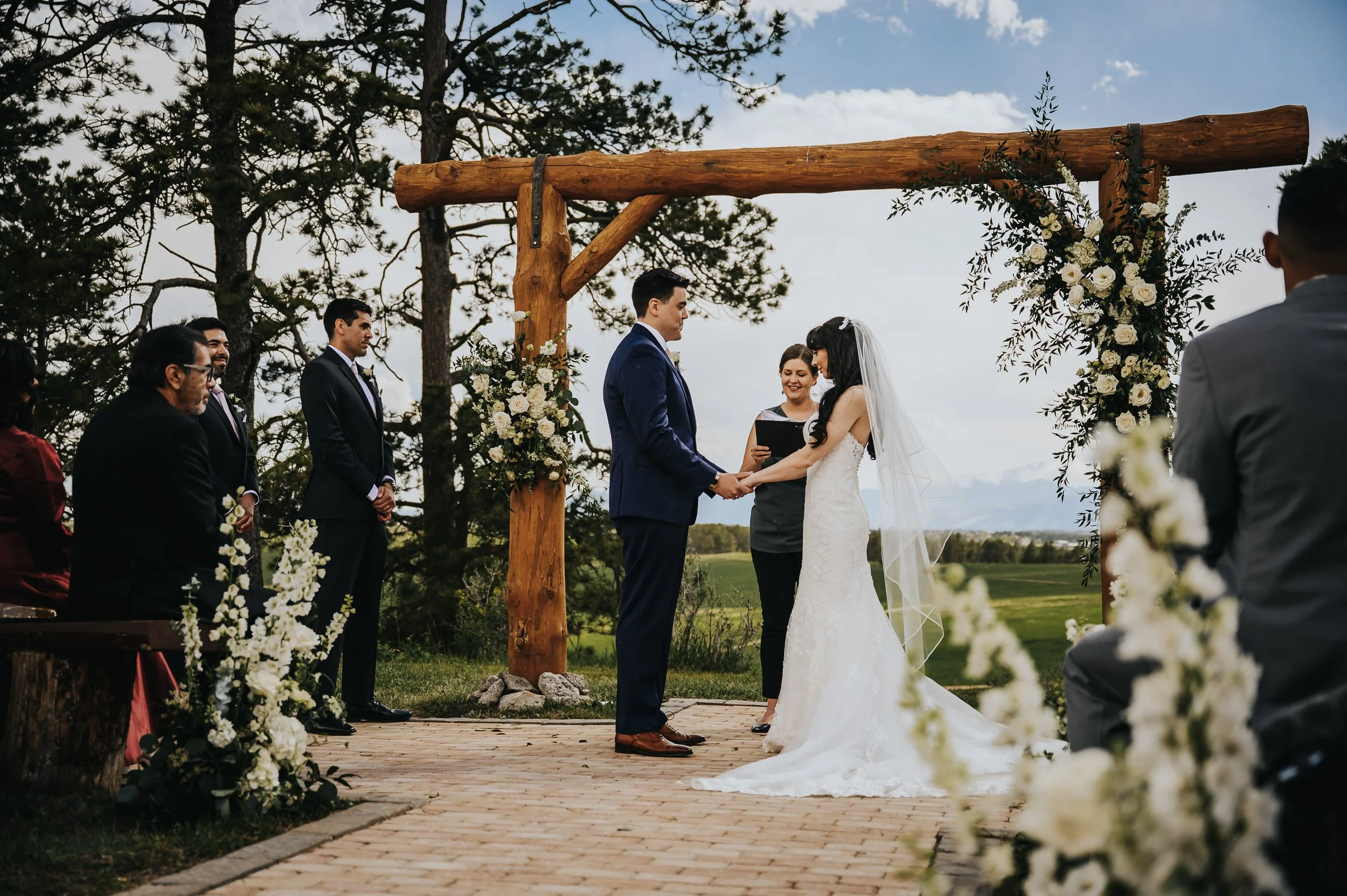Wedding ceremony under a wooden arch at Younger Ranch in Colorado Springs.