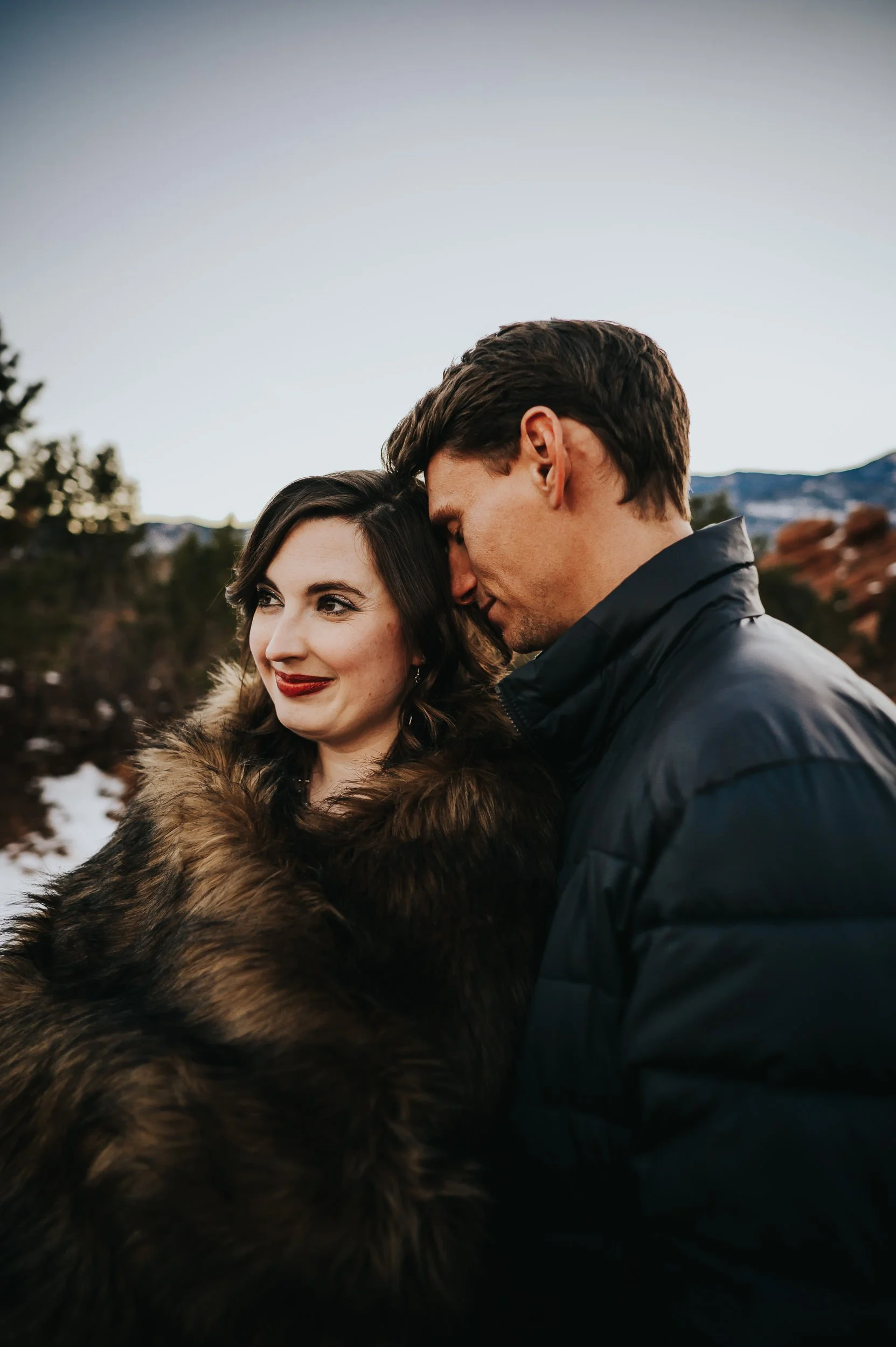 Expecting mother wrapped in faux fur blanket during Garden of the Gods maternity session.