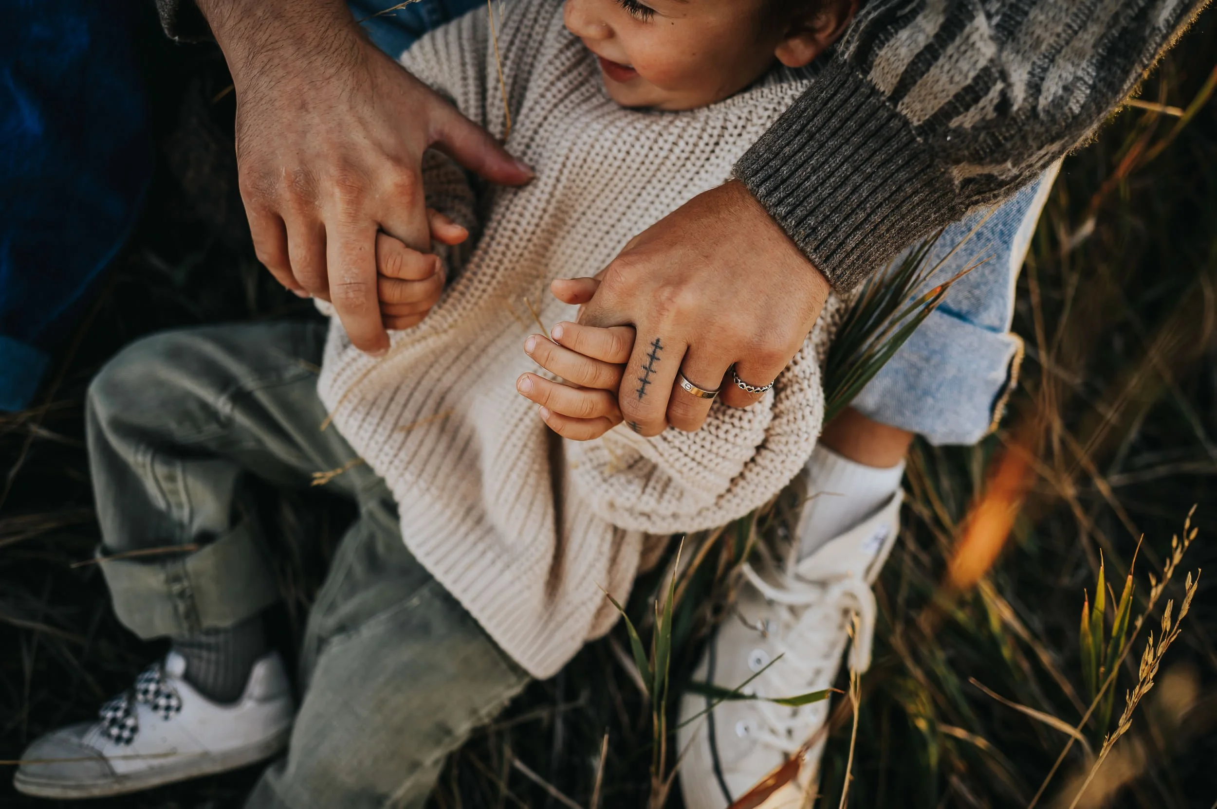 Close up detail of father and son cuddling in the grass.