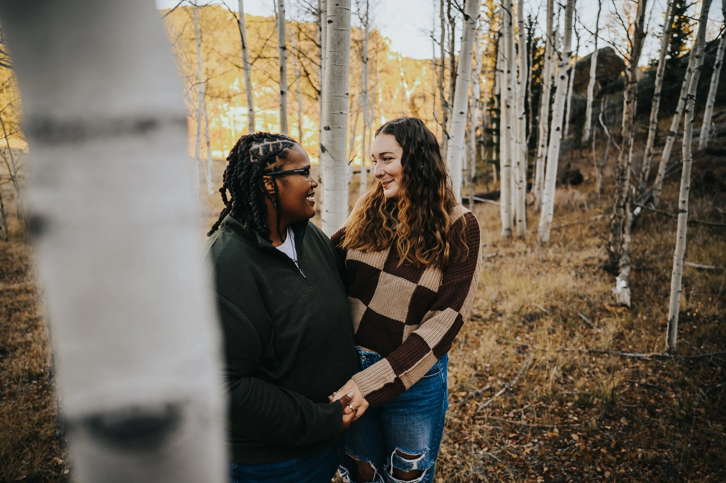 Two brides in everyday clothes sharing a quiet moment before their ceremony.