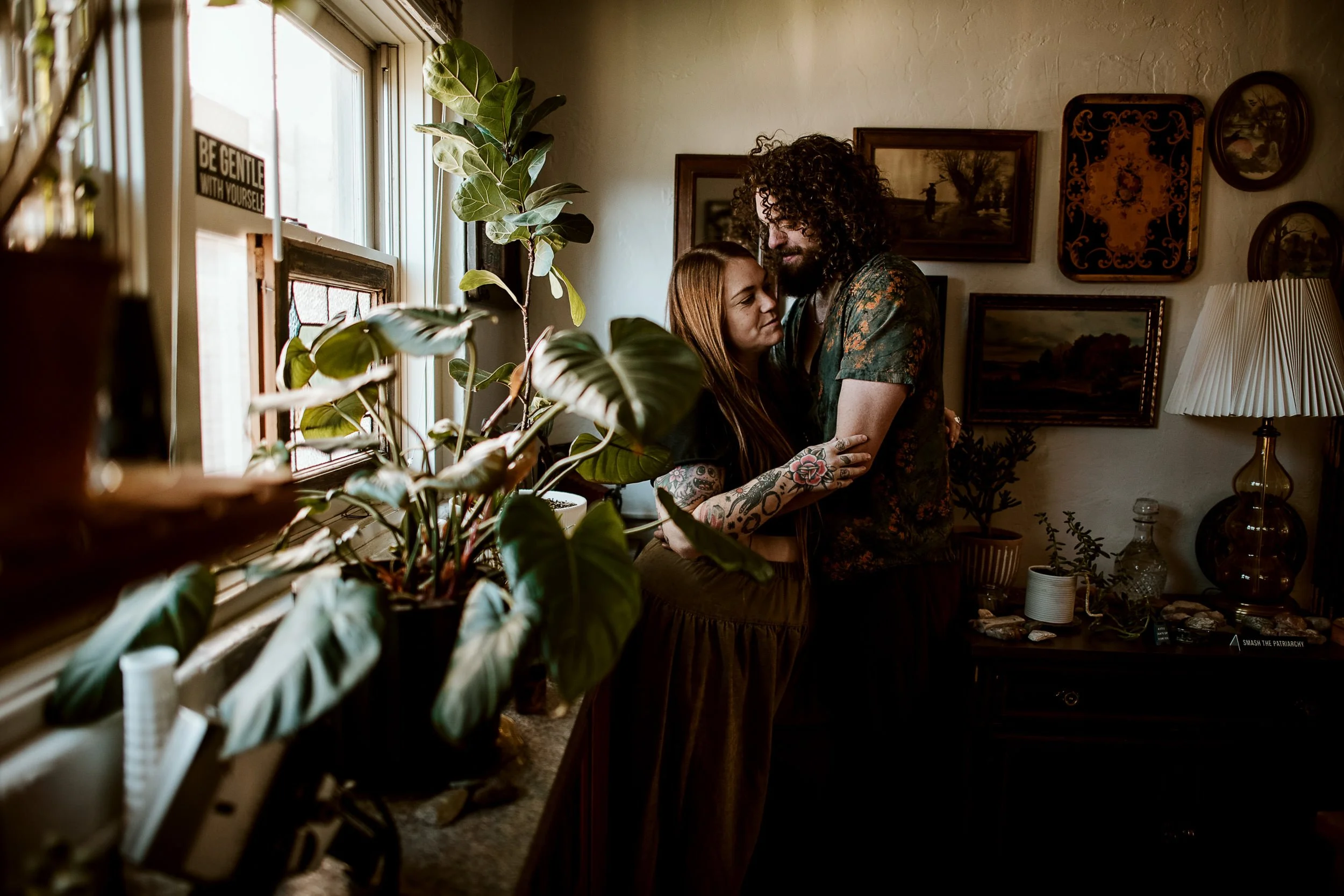 Colorado Springs photographer Sandy Patterson and her partner embracing by a window surrounded by houseplants.