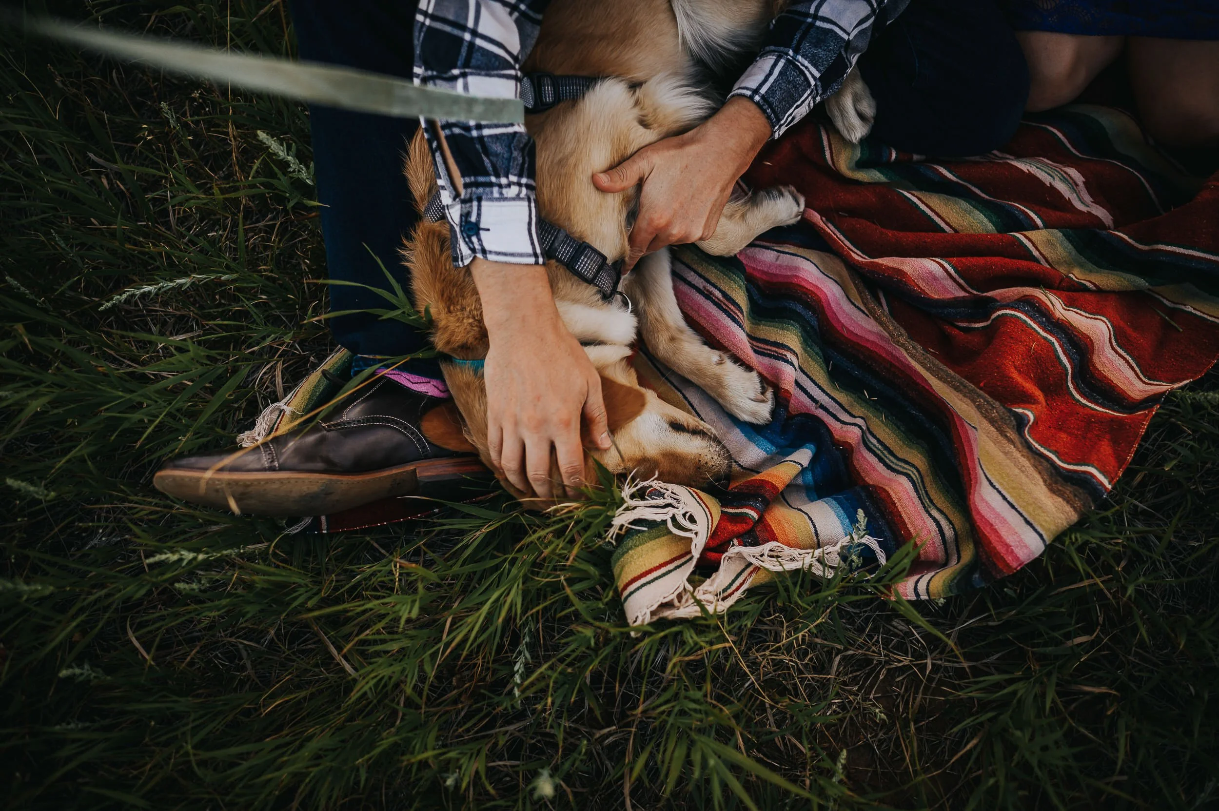 A closeup of a couple's hands intertwined on a colorful woven blanket, warm and intimate.